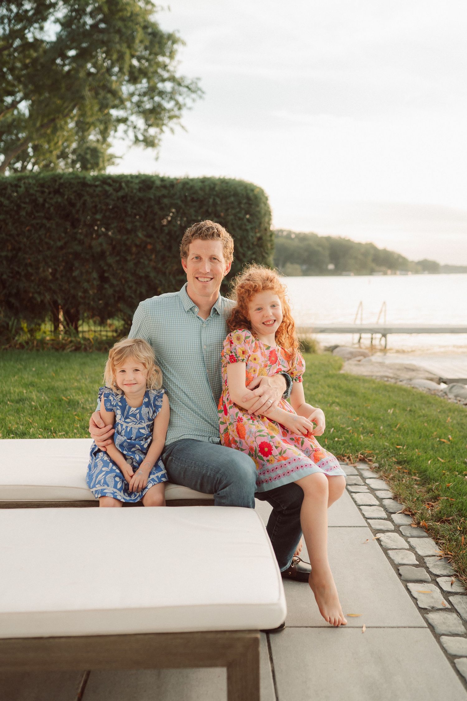 Casual outdoor family portraits on a stone patio overlooking a scenic waterfront view.