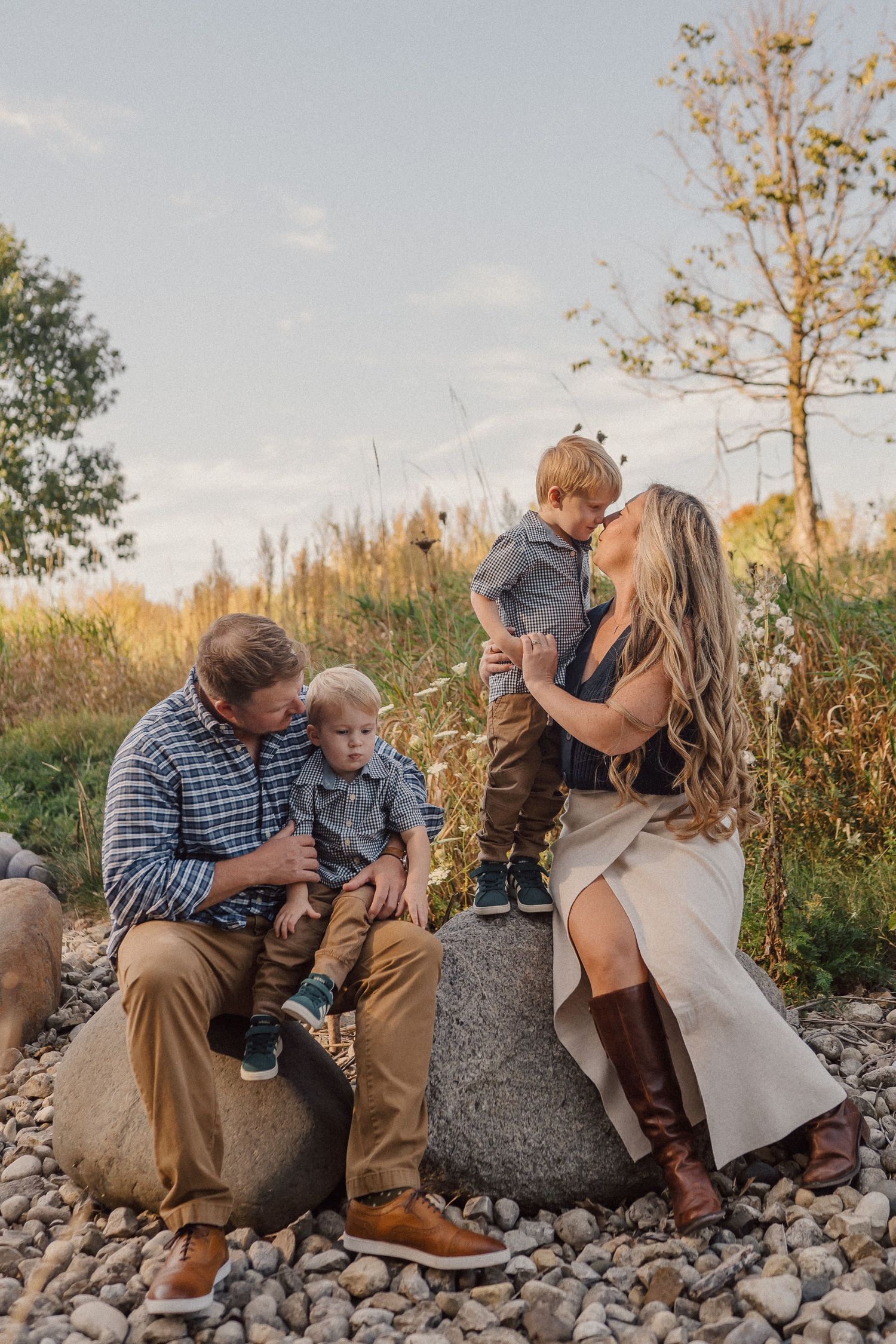 A family shares tender moments together sitting on rocky terrain during a golden sunset photoshoot.