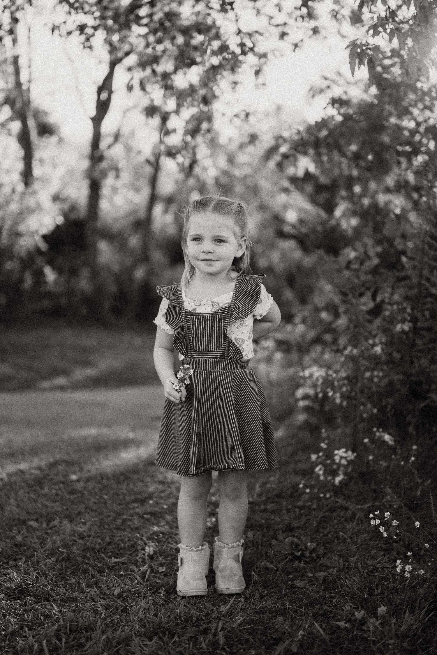 Black and white portrait series of a small child playing in a natural outdoor setting.