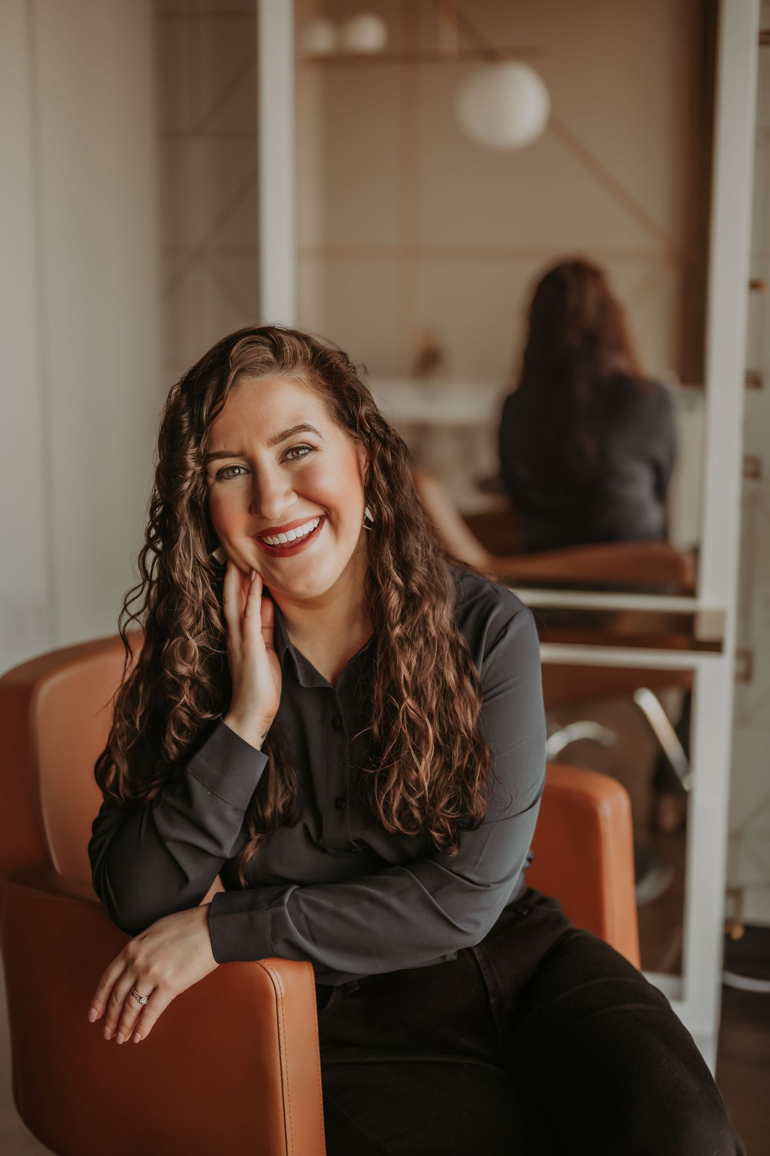Candid portrait in salon chair showing joyful expression and warm interior lighting.