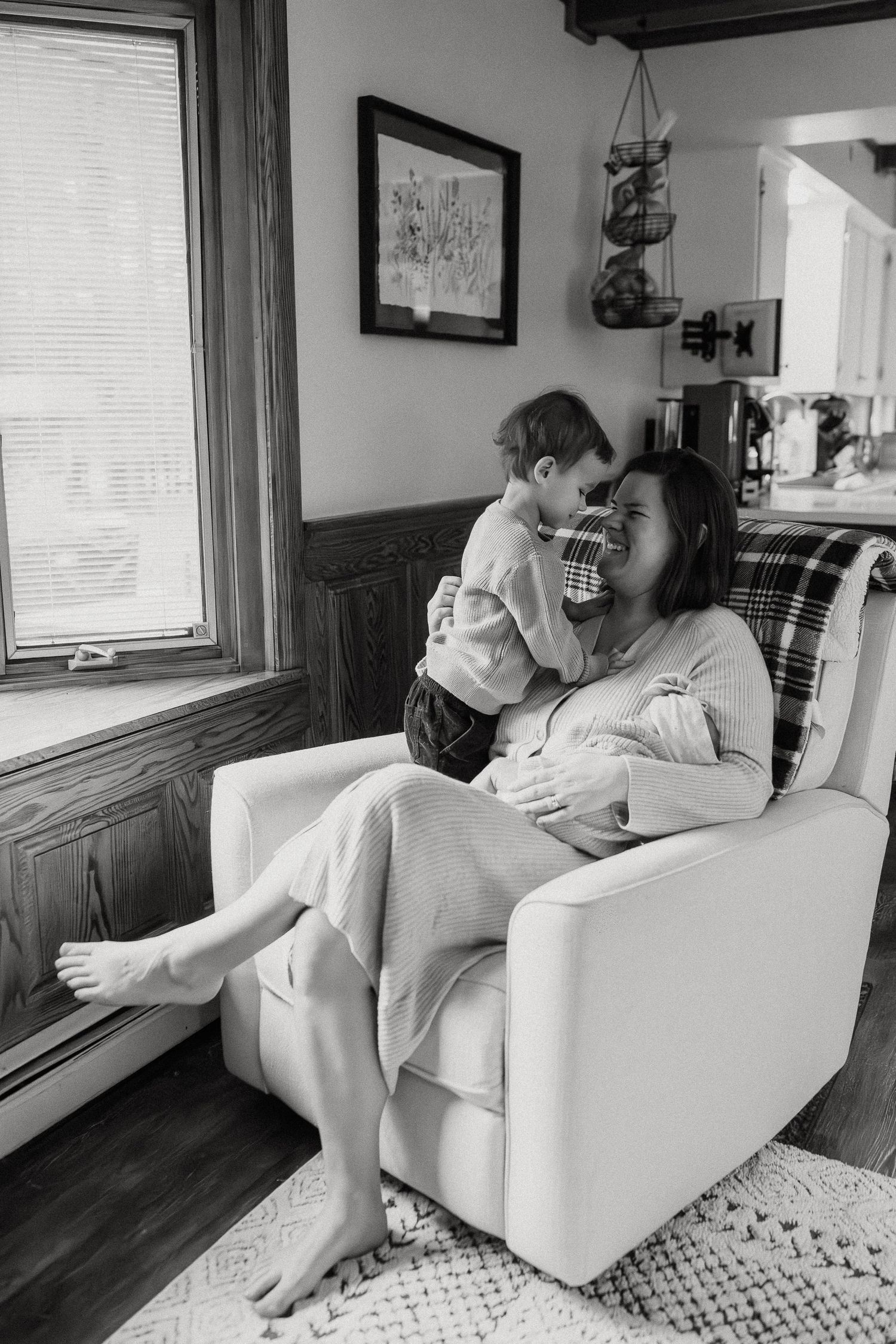 Black and white photo series showing quiet moments between parent and infant on white armchair.
