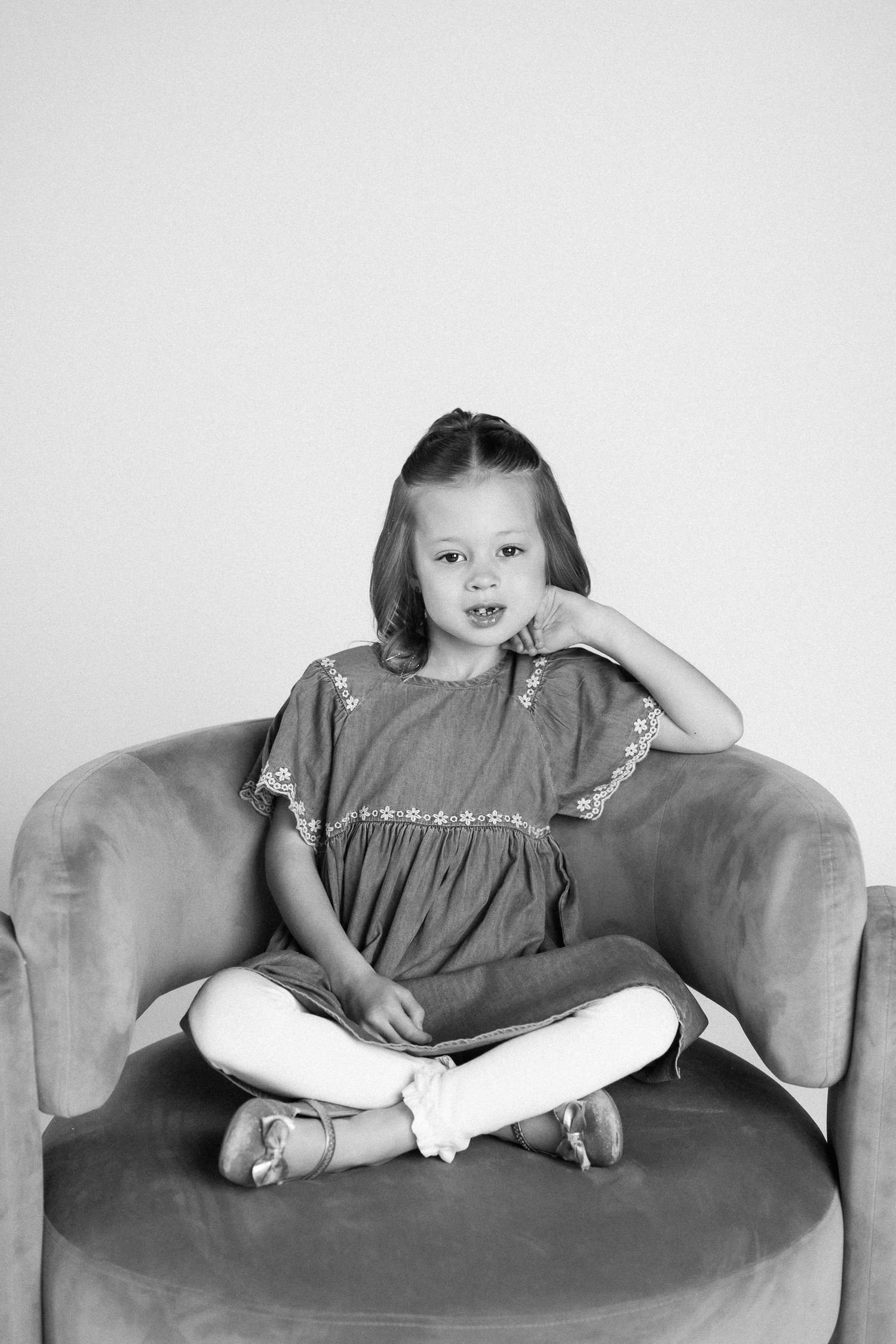 A series of black and white photos showing a child lounging on a couch in different relaxed poses.