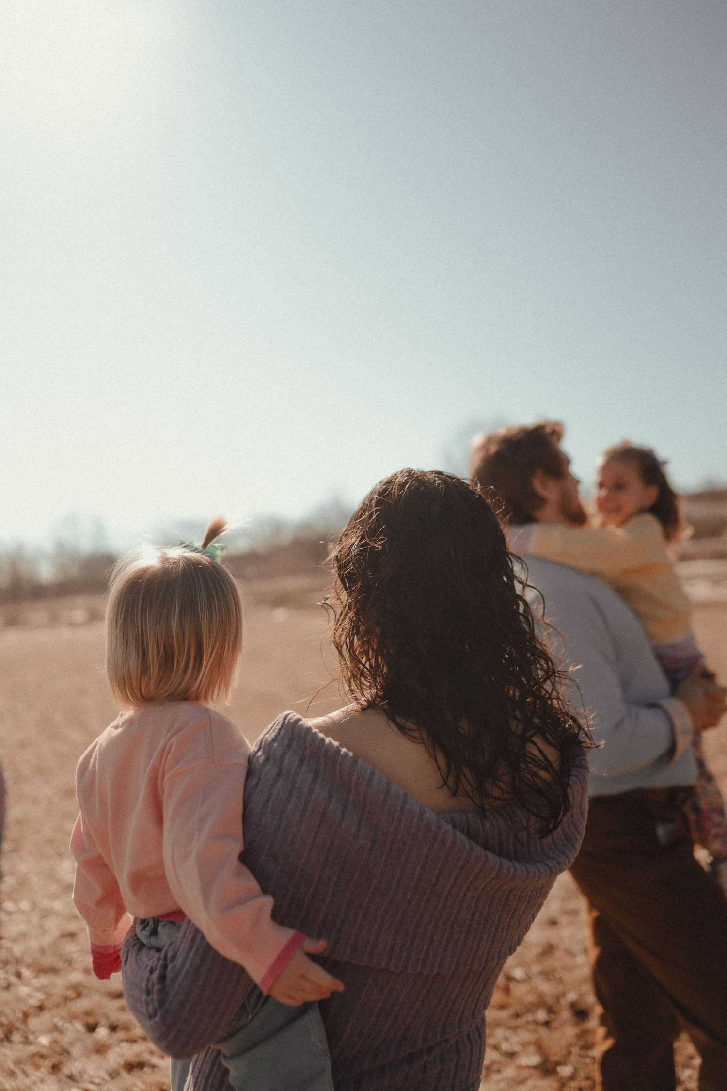 A group of people walk together through a sunlit field on an autumn afternoon.