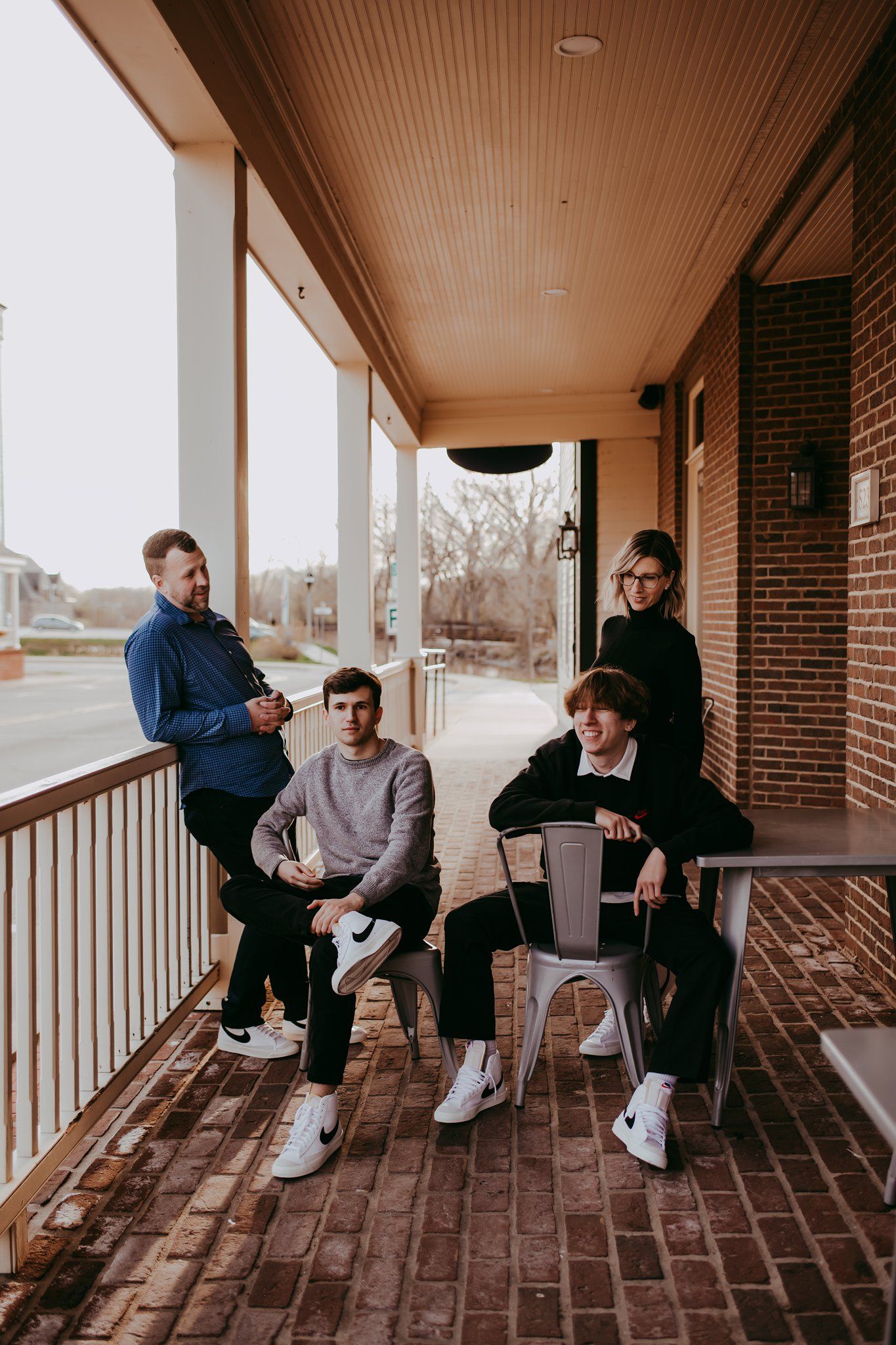 Group relaxing on covered brick porch with white columns and wood ceiling.