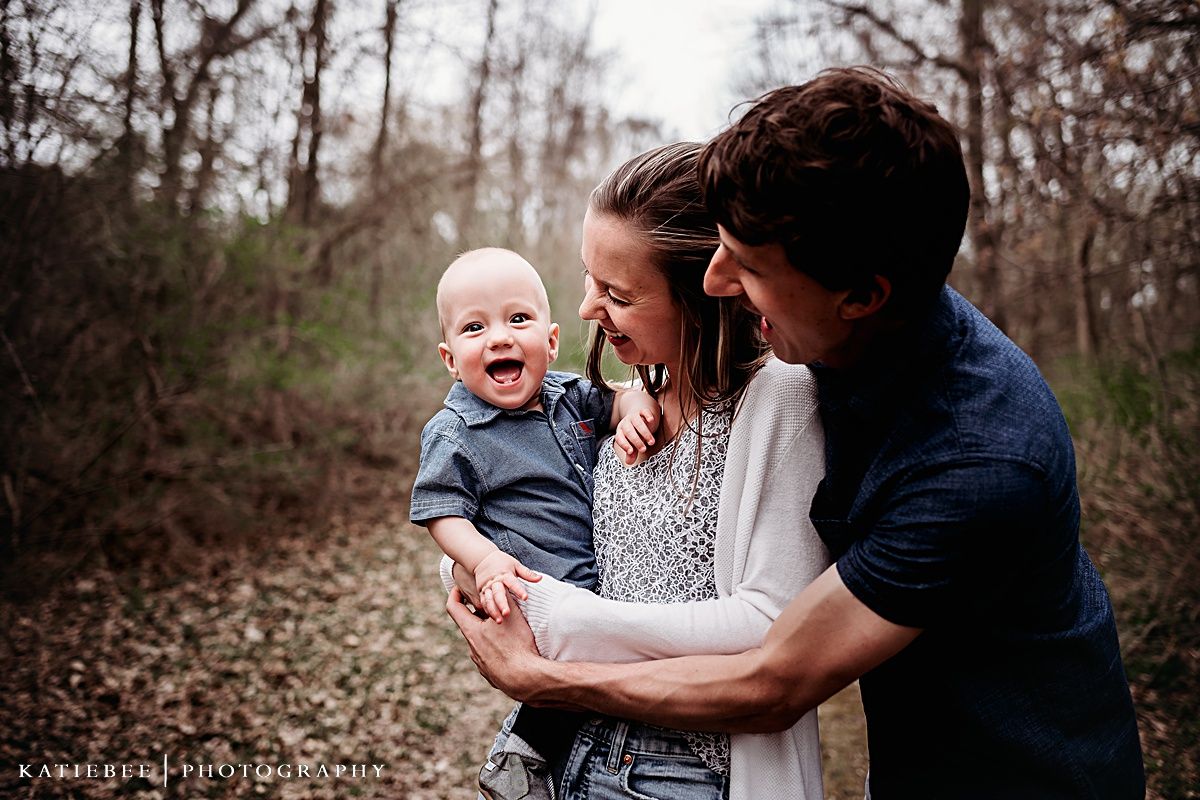 Candid family moment capturing laughter on wooded trail.