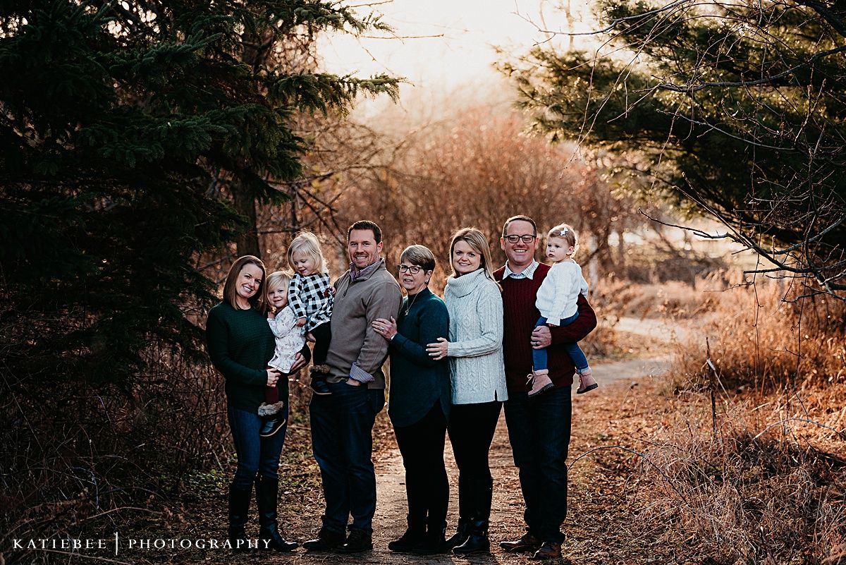 Group portrait of family members standing together on a nature trail surrounded by evergreen trees.
