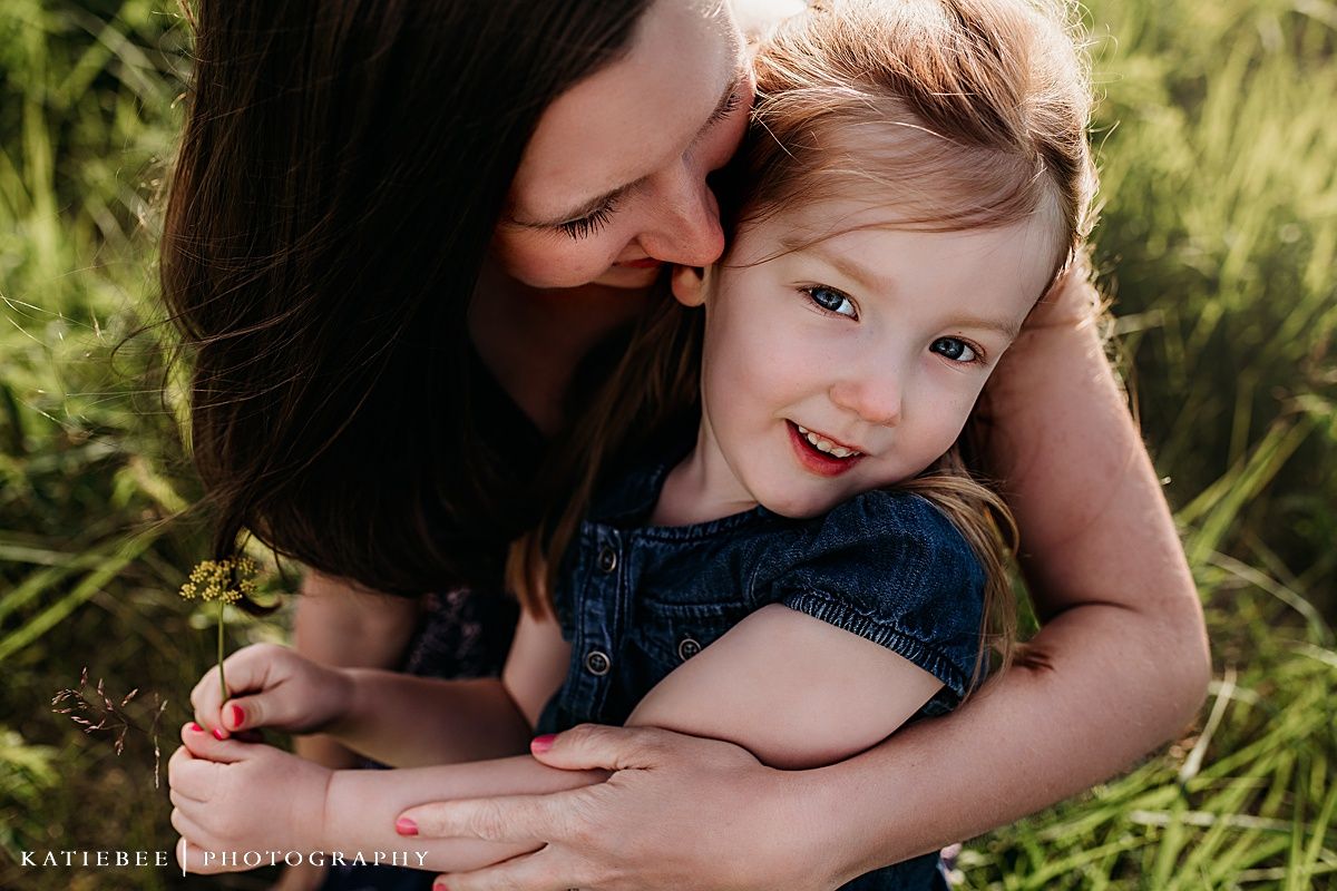 Tender embrace captured in close-up among tall grass during golden hour.