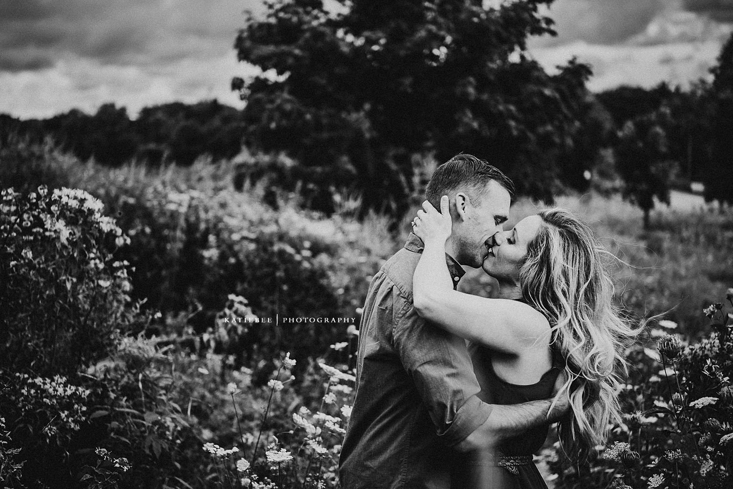 Black and white portrait of romantic embrace in a wildflower field.