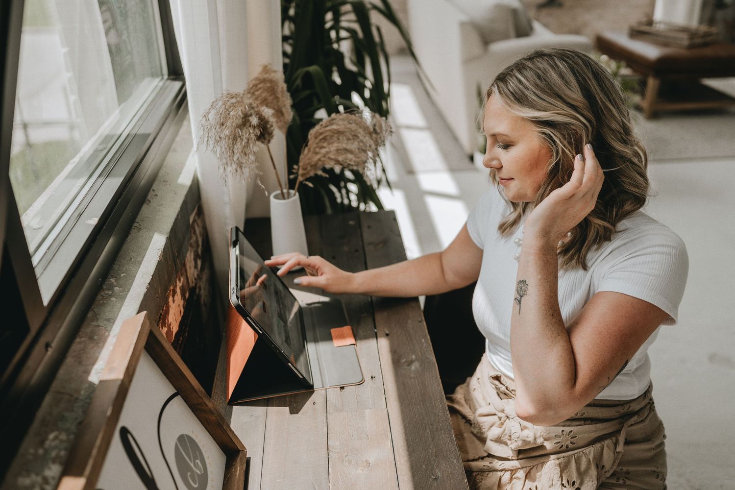 Woman in white shirt looking at record player in bright modern living room.