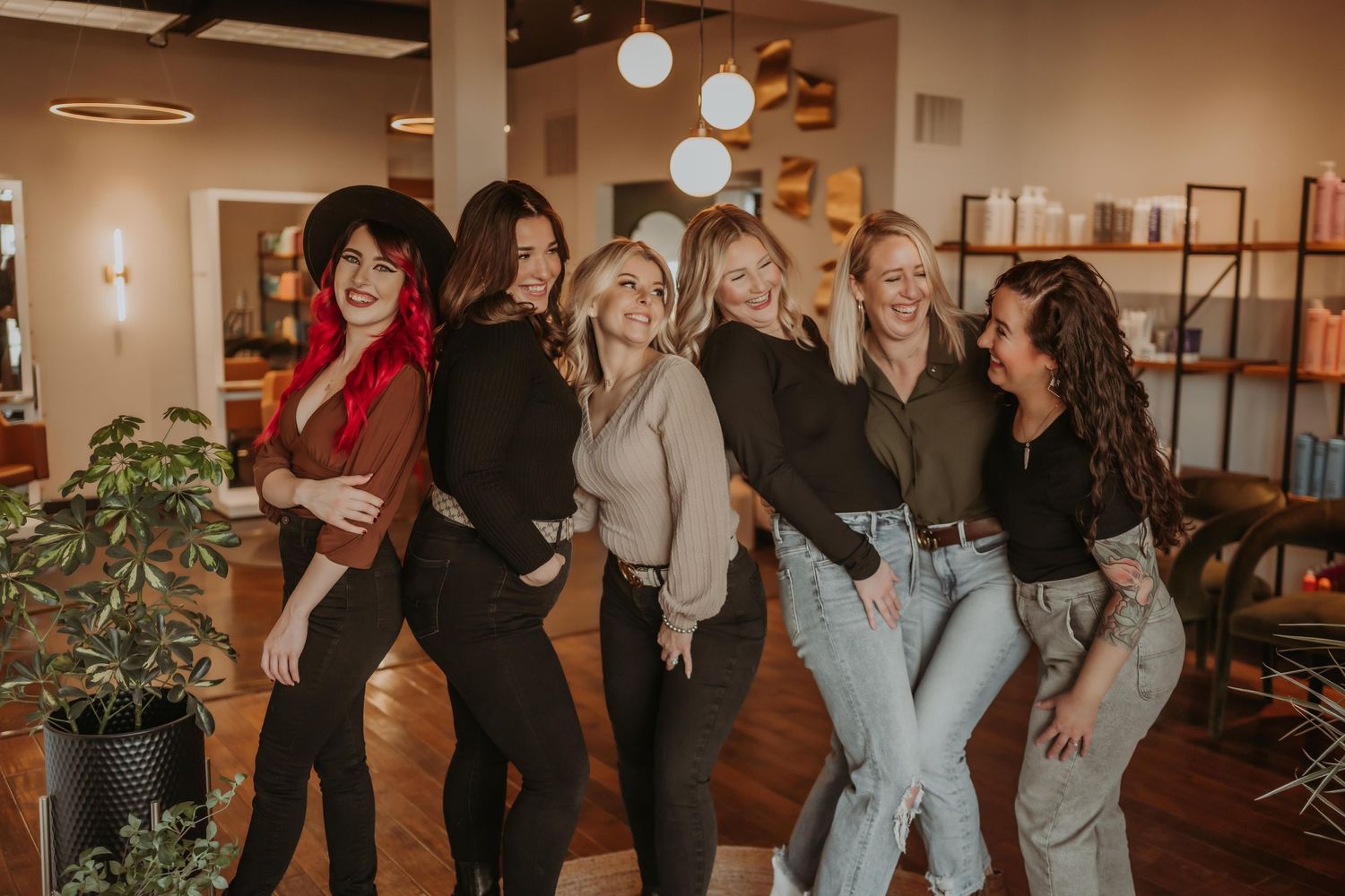 Group of friends posing playfully together in casual outfits against indoor backdrop.