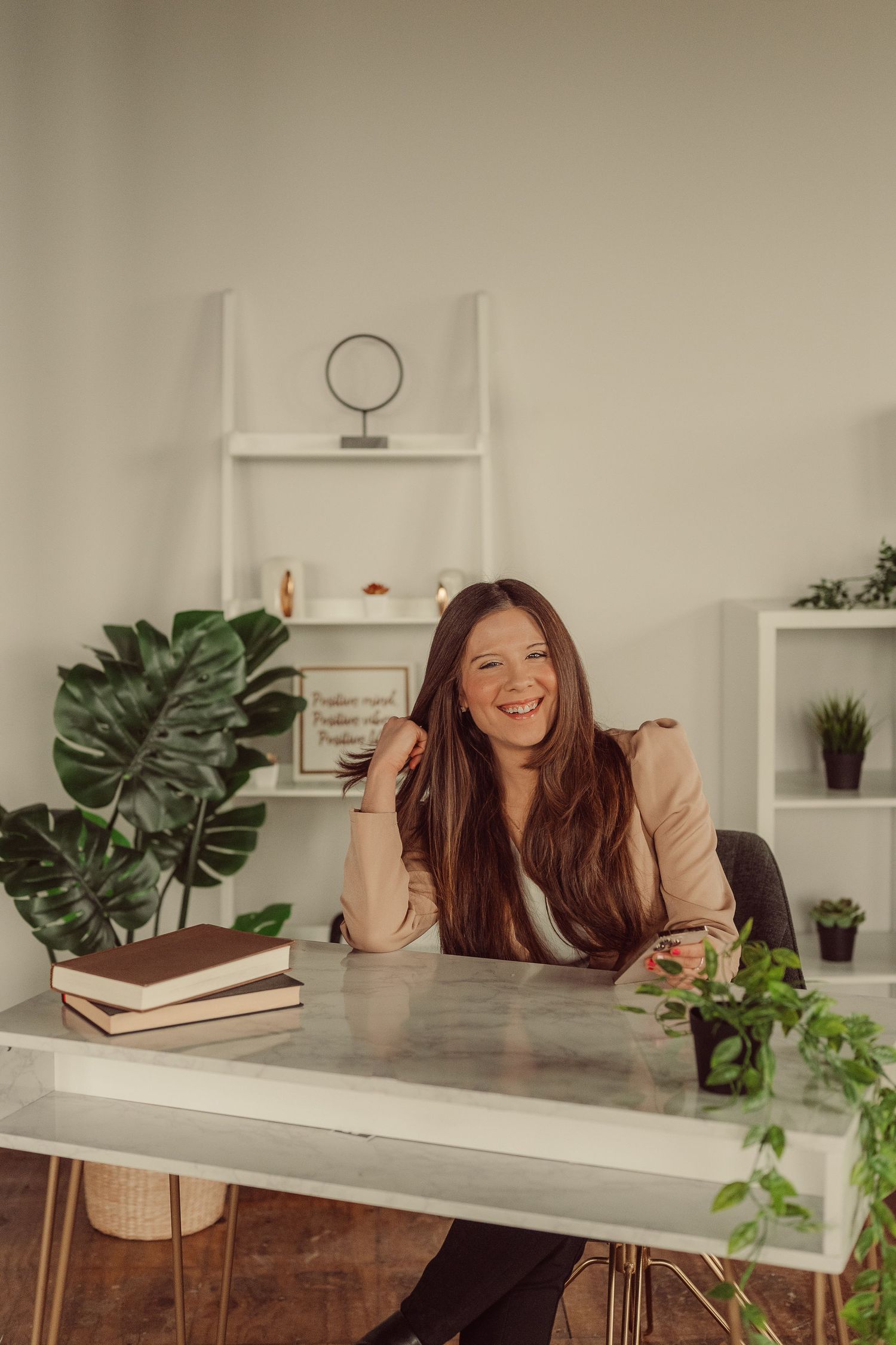 Bright workspace featuring concrete desk, ladder shelf storage, and lush indoor plants.