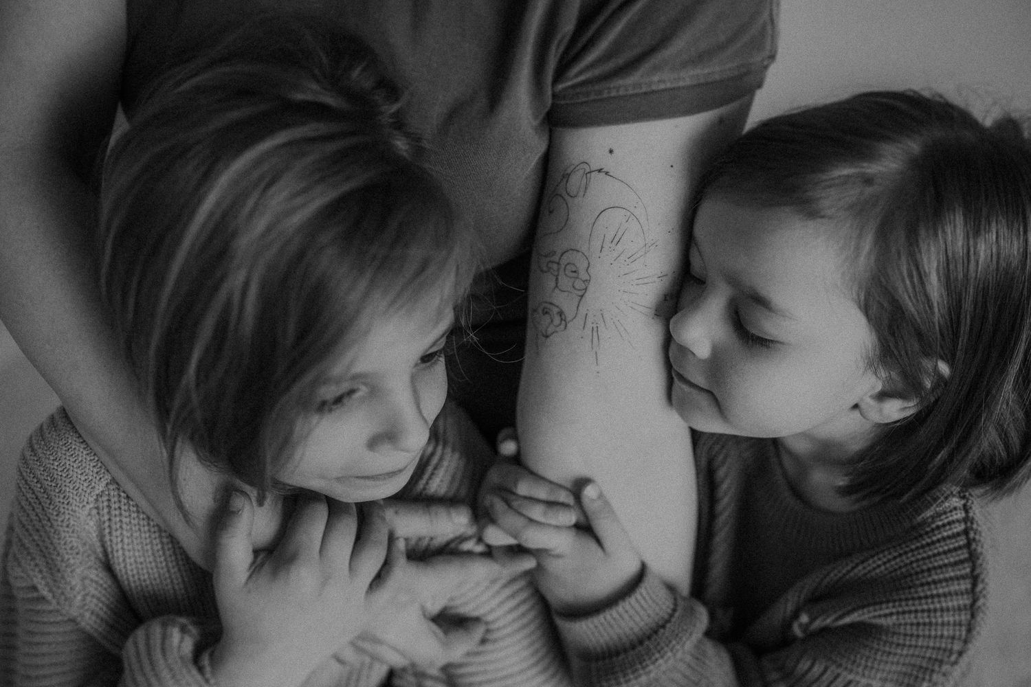A candid black and white photo capturing a playful moment between children smiling and laughing.