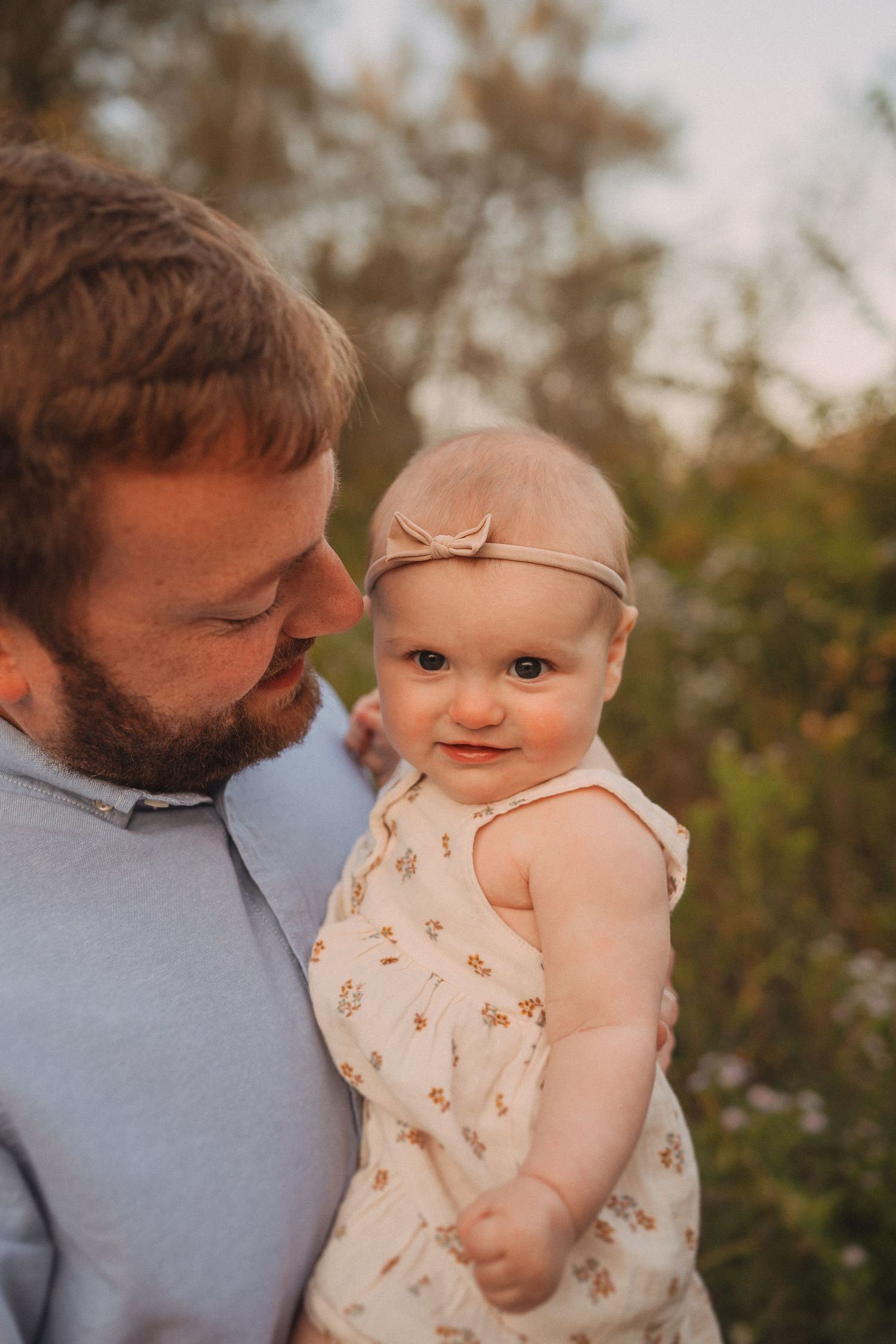 A sweet moment between parent and baby against a sunset-lit natural backdrop.
