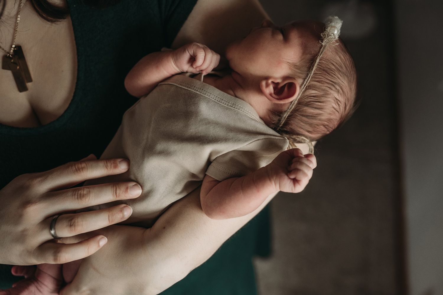 Tender moment with sleeping newborn swaddled in neutral fabric.