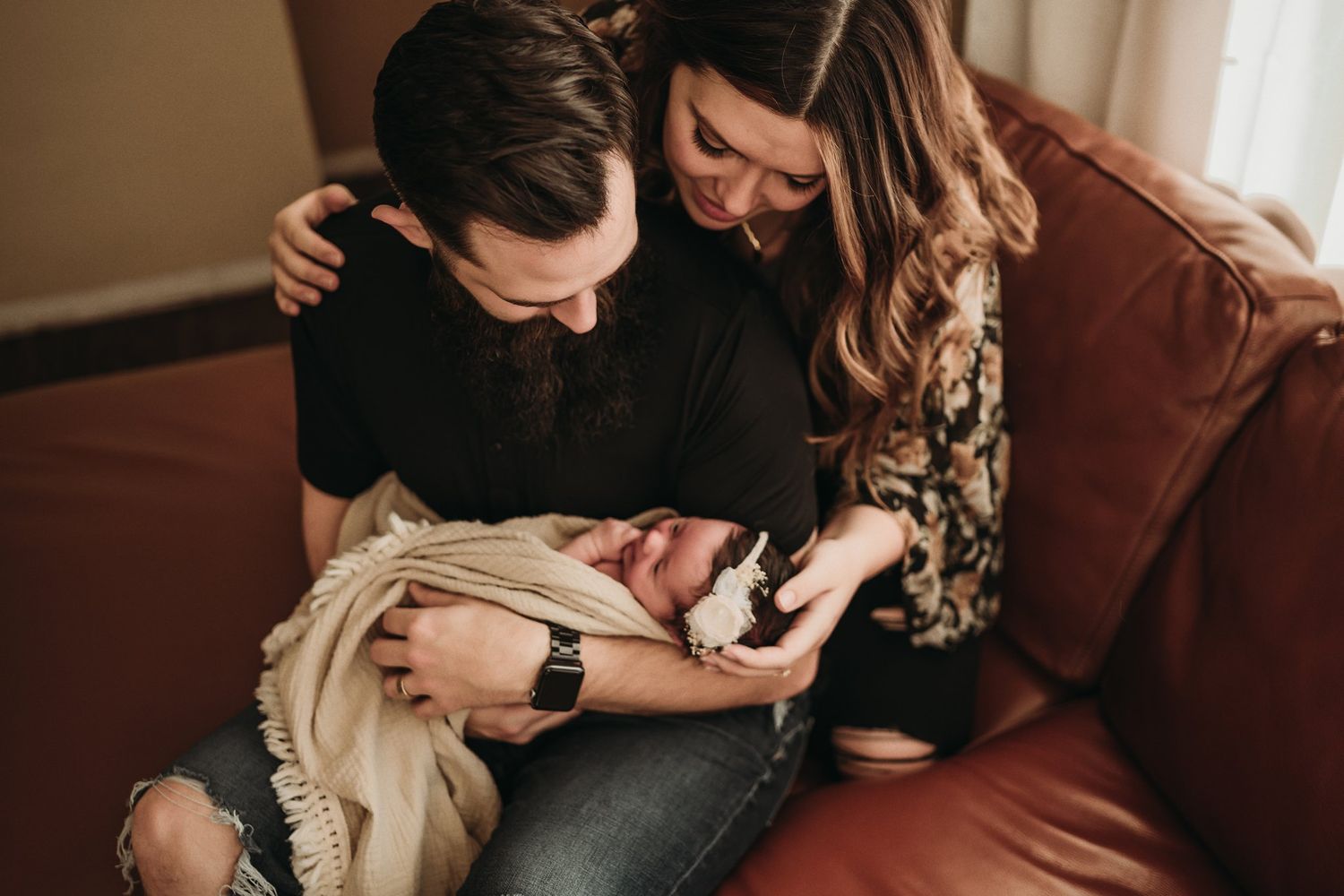 Intimate family moment on leather sofa in warm-toned indoor setting.