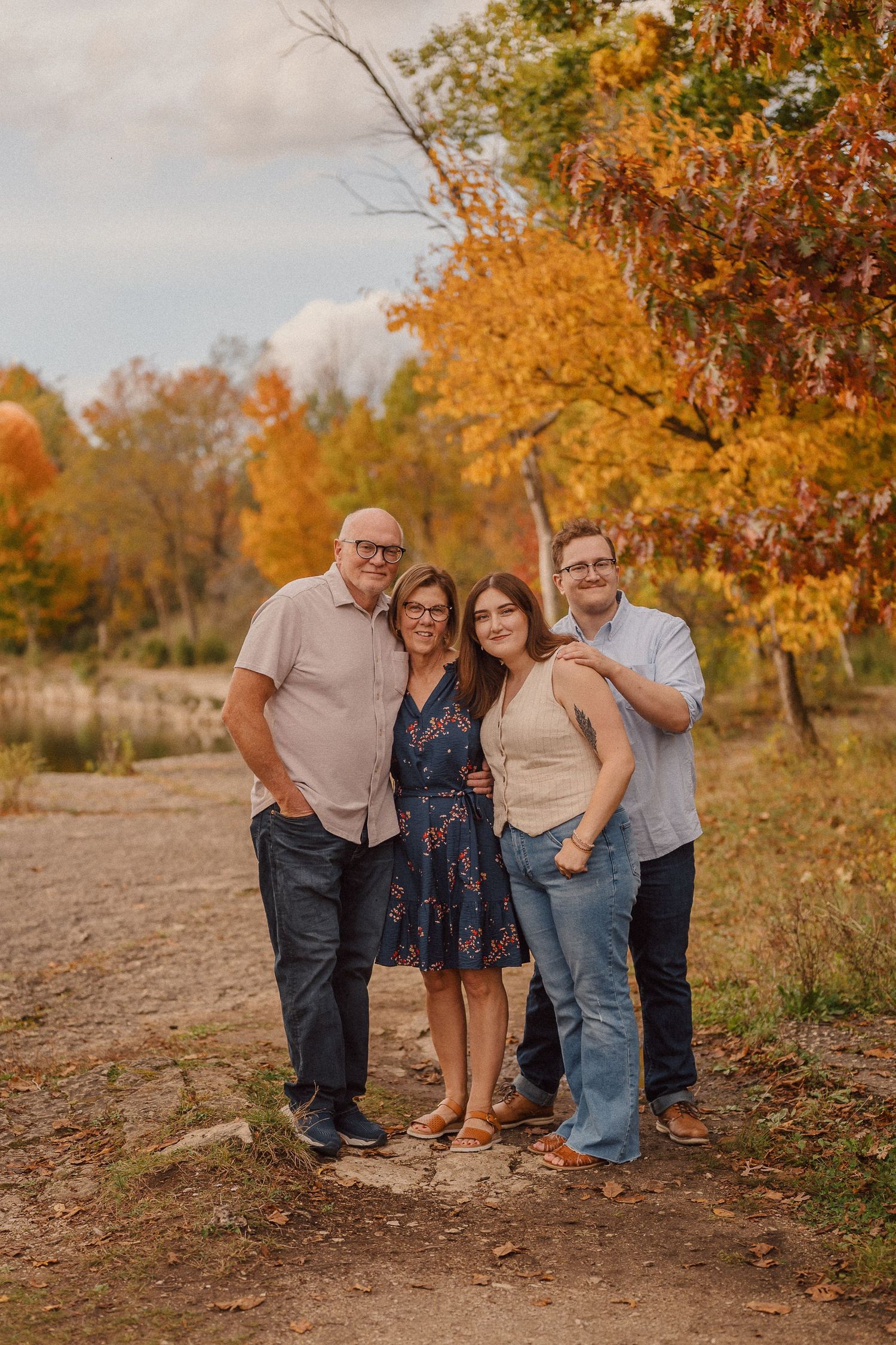 A group poses together on a hillside path during a beautiful fall afternoon with orange trees in the background.