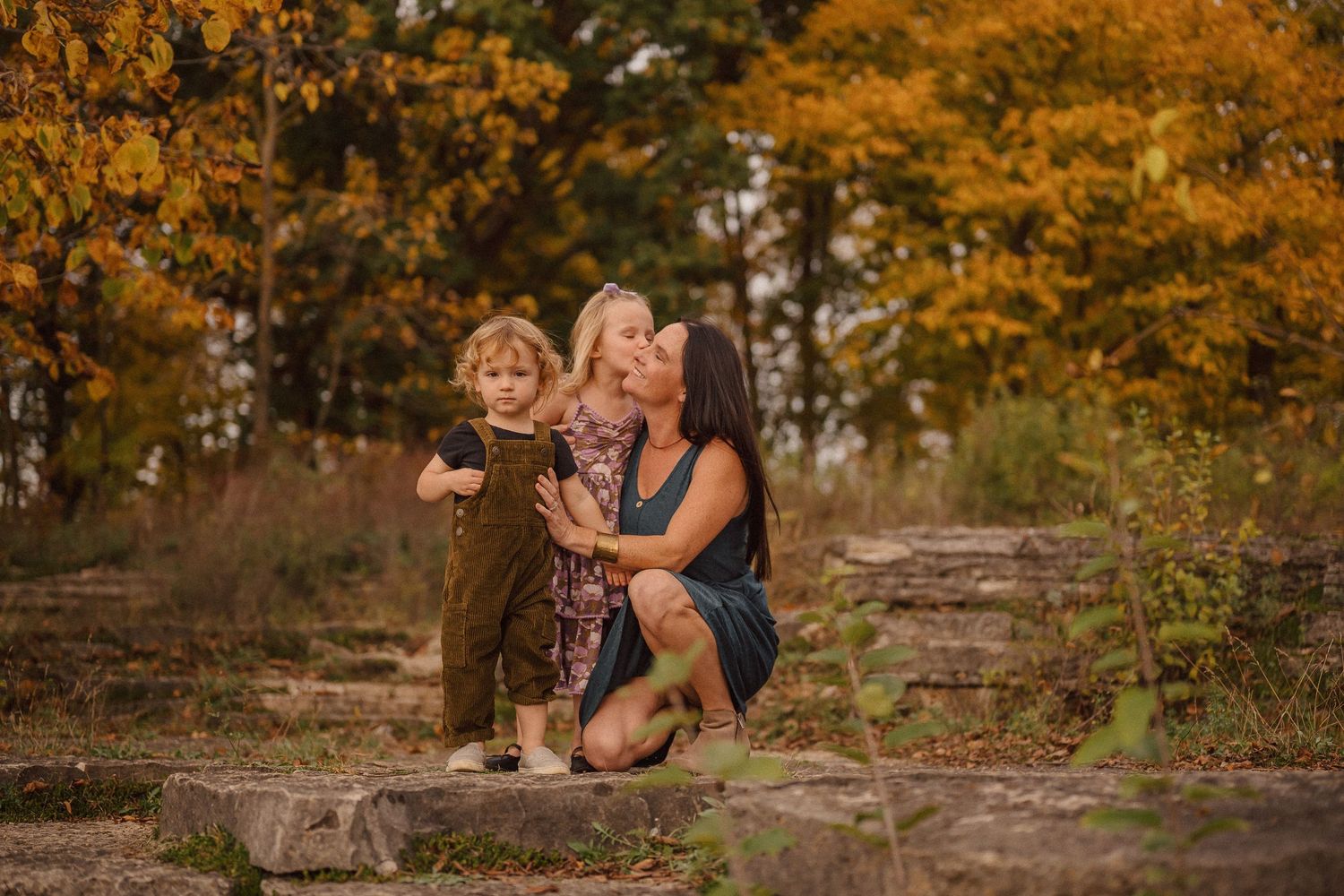 People sitting together on rocks surrounded by vibrant fall foliage and golden trees.