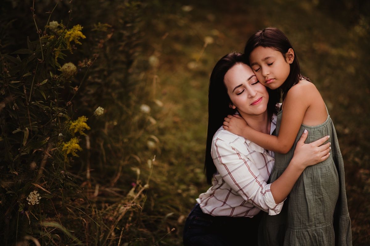 Tender embrace between mother and child on woodland path during golden hour.