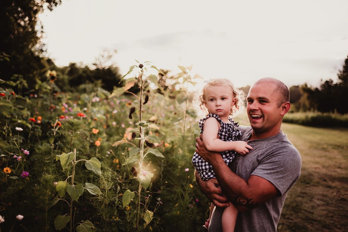 A sweet moment captured in a blooming garden with sunflowers and wildflowers at sunset.
