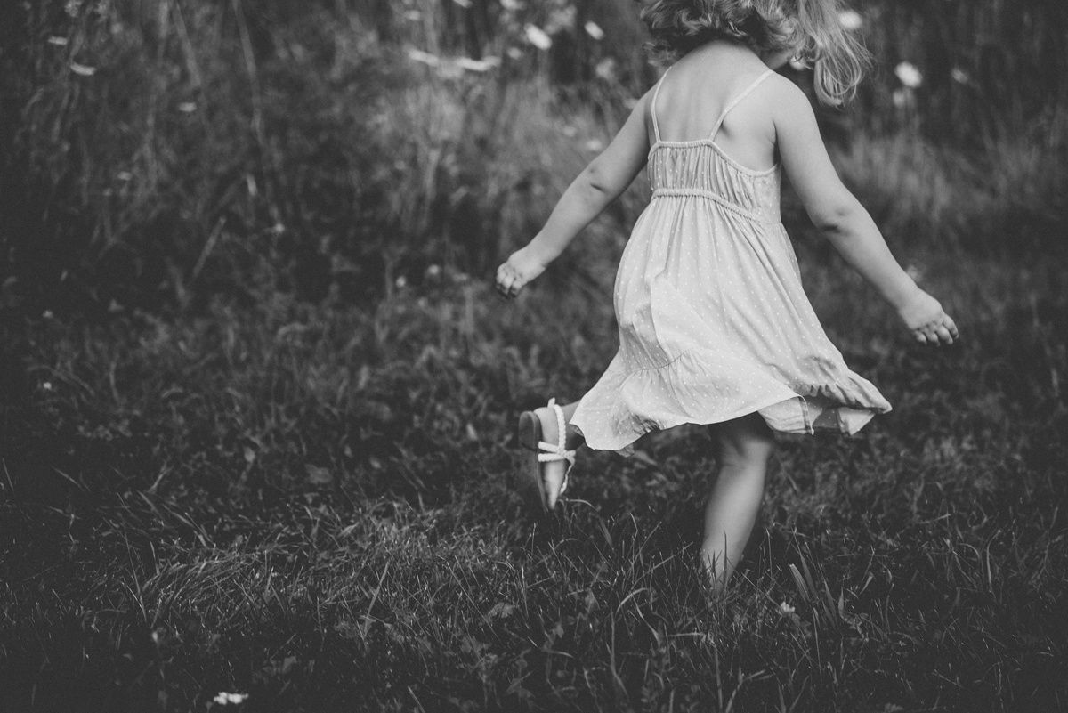 Black and white image of twirling dress movement in a grassy field.