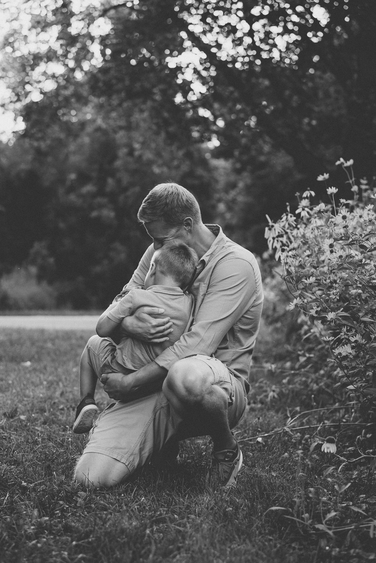 Intimate black and white portrait captured in garden setting among flowering plants.