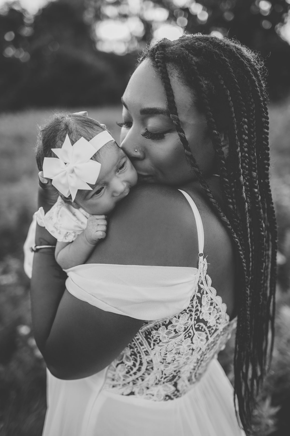 An intimate black and white portrait of a mother and baby sharing a tender moment.