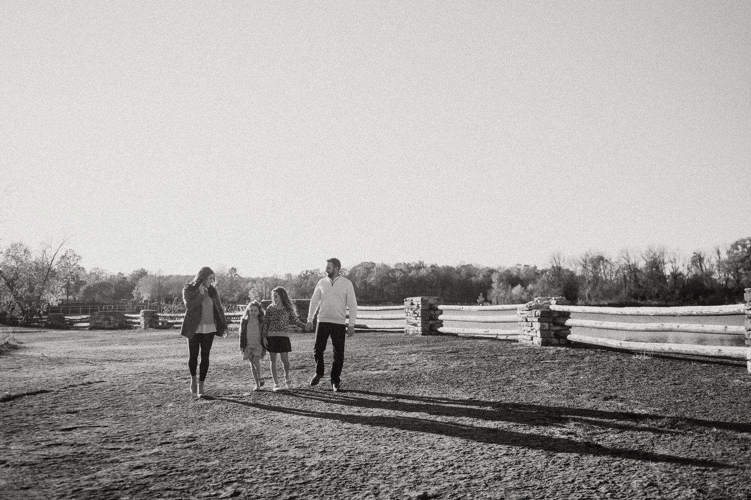 Couple and horses walking together in a scenic field during sunset creating silhouettes against the sky.