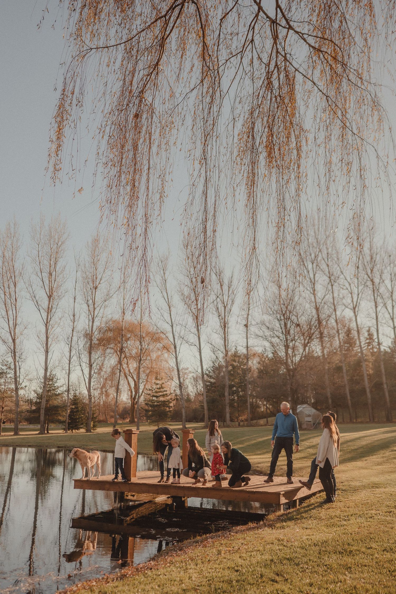 People gathered on a wooden dock by a lake during late autumn.