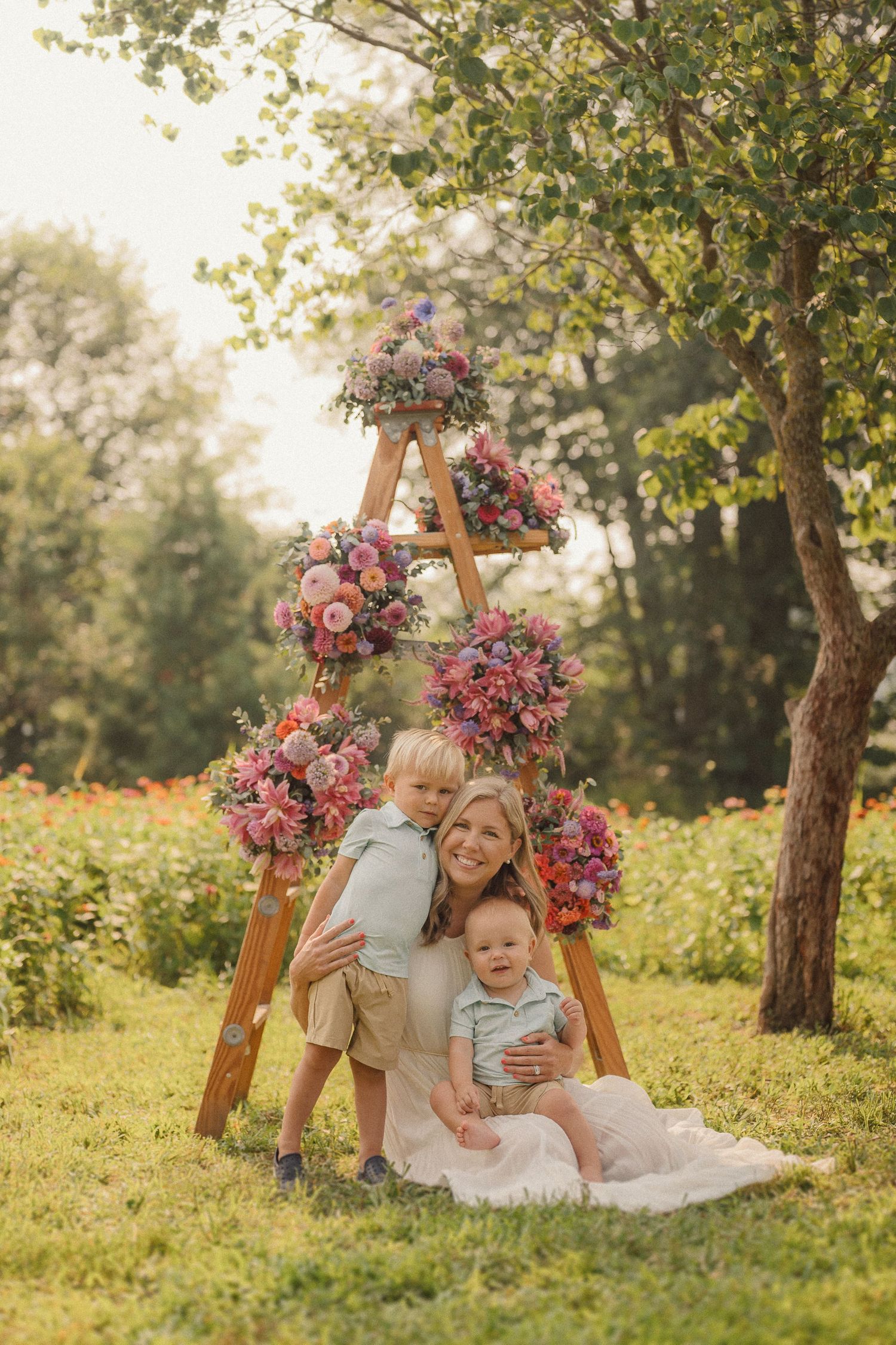 Three images showing subjects lounging on grass near decorative wooden A-frame stands adorned with pink and red flowers.