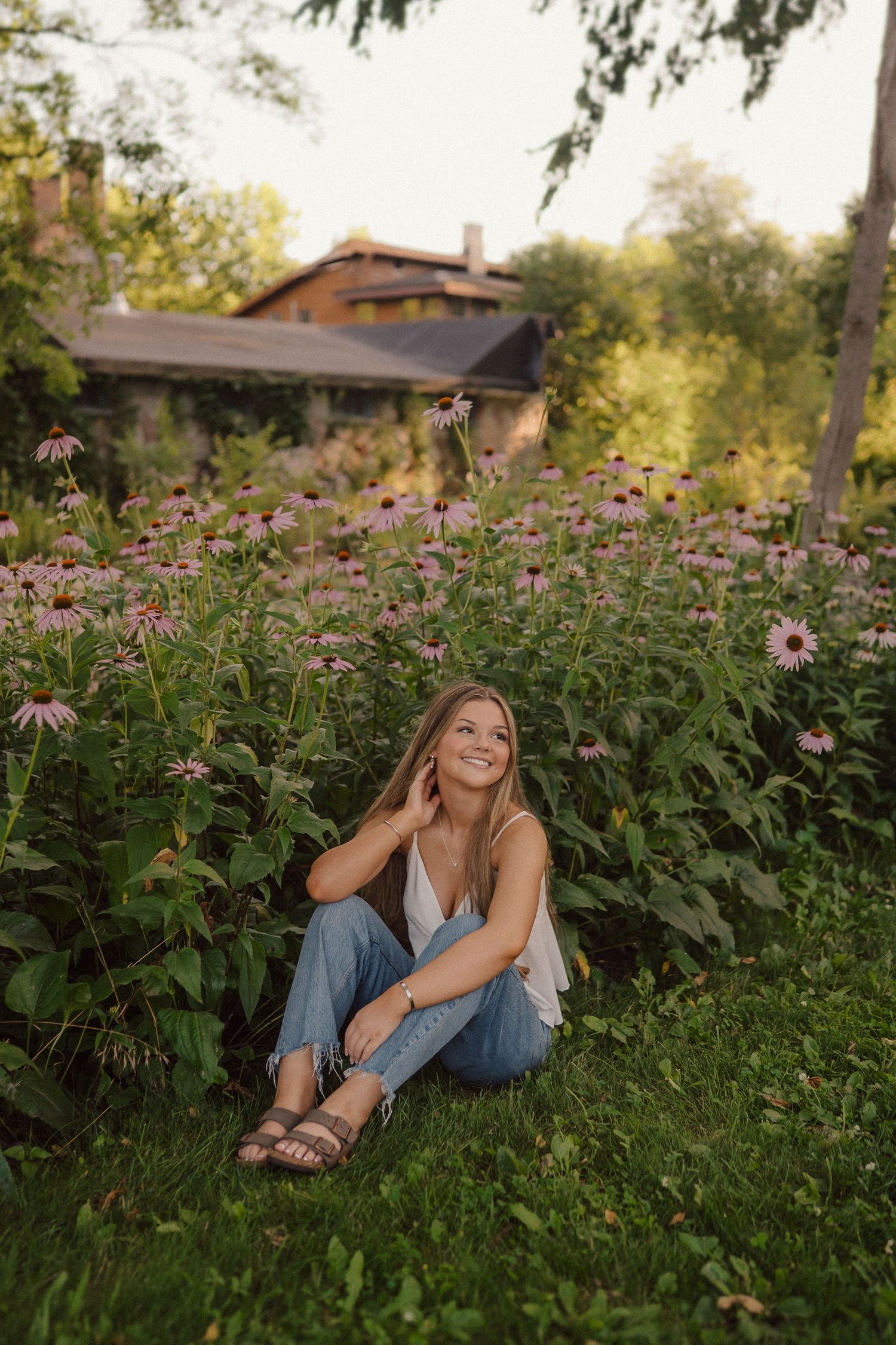 A photo shoot in a blooming flower garden during golden hour with pink flowers in the background.