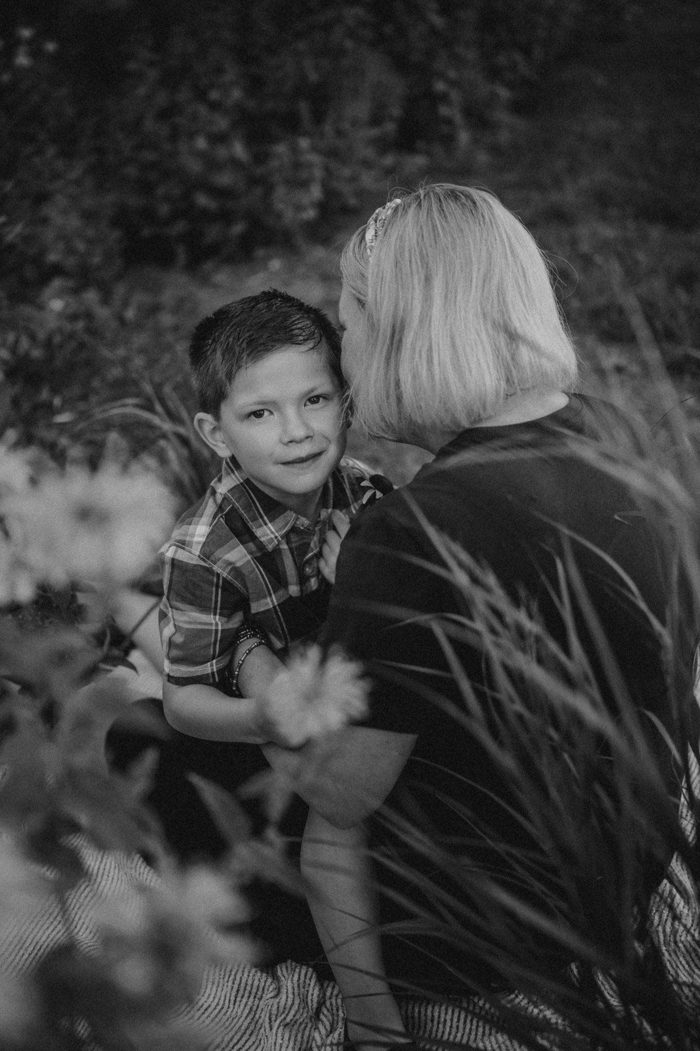 A sweet black and white portrait capturing an intimate moment among garden foliage.