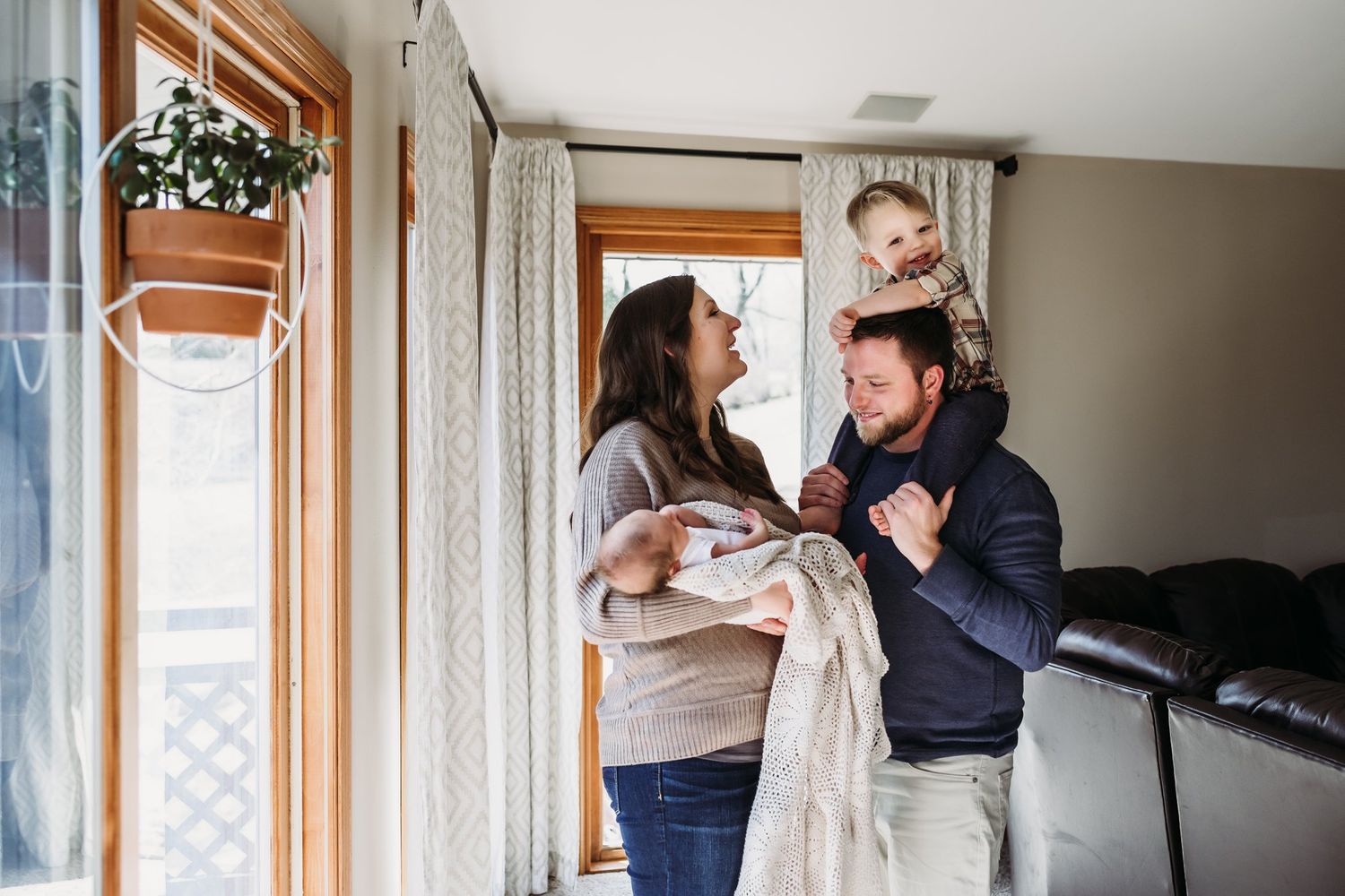 A sweet family interaction by the window with curtains and natural light streaming in.