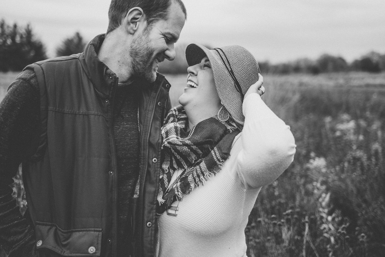 Black and white intimate portrait of couple sharing tender moment in outdoor field setting.