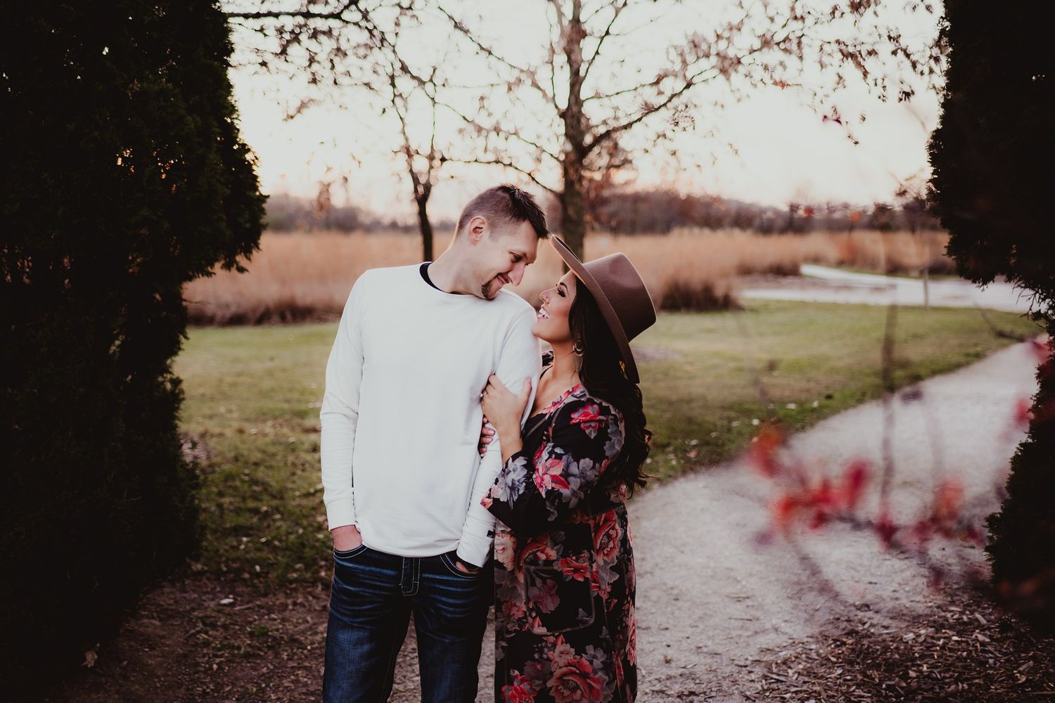 Intimate moment shared between couple on tree-lined path in autumn.