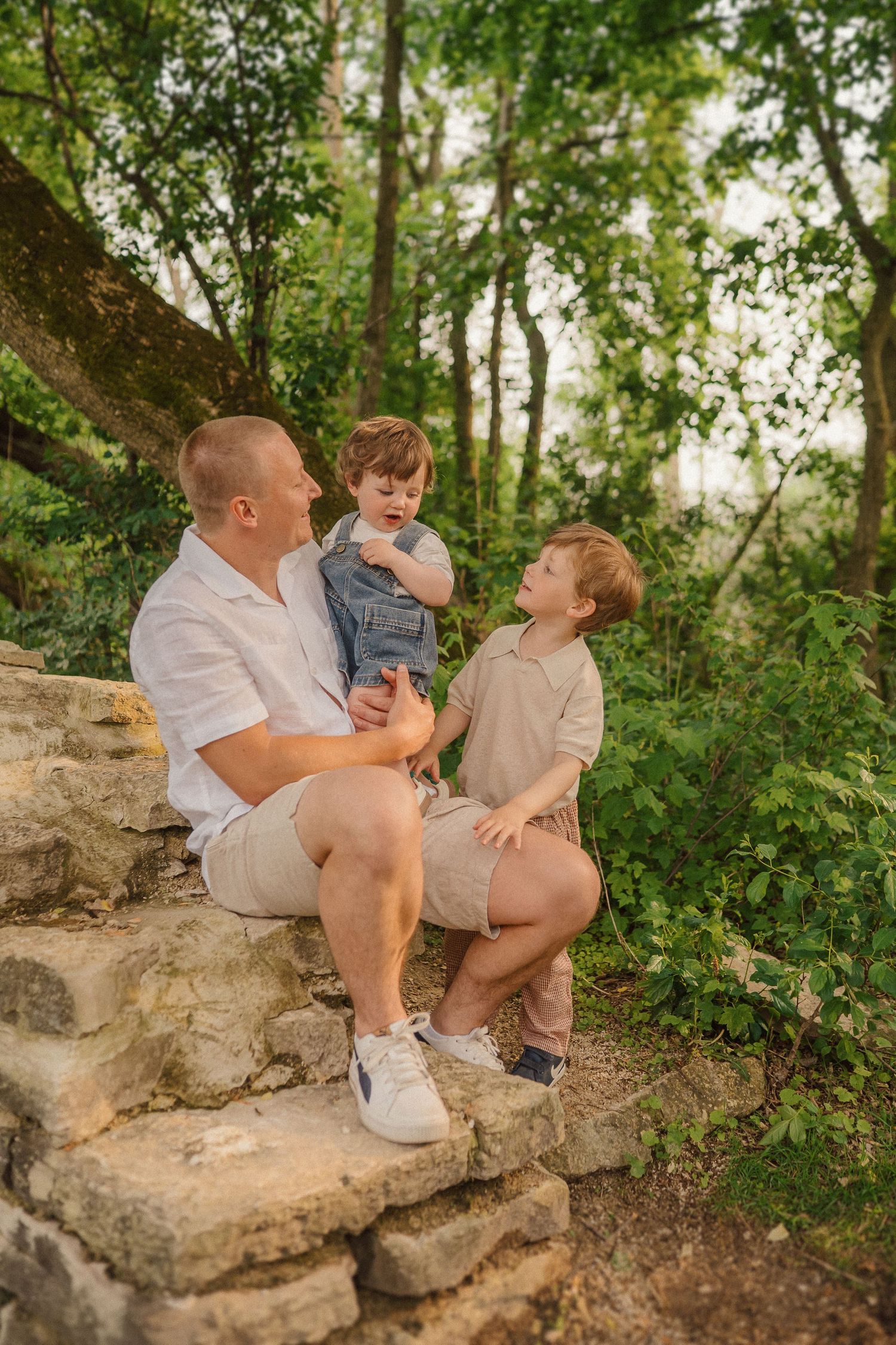 People sitting together on a natural limestone ledge surrounded by lush green foliage in an outdoor setting.