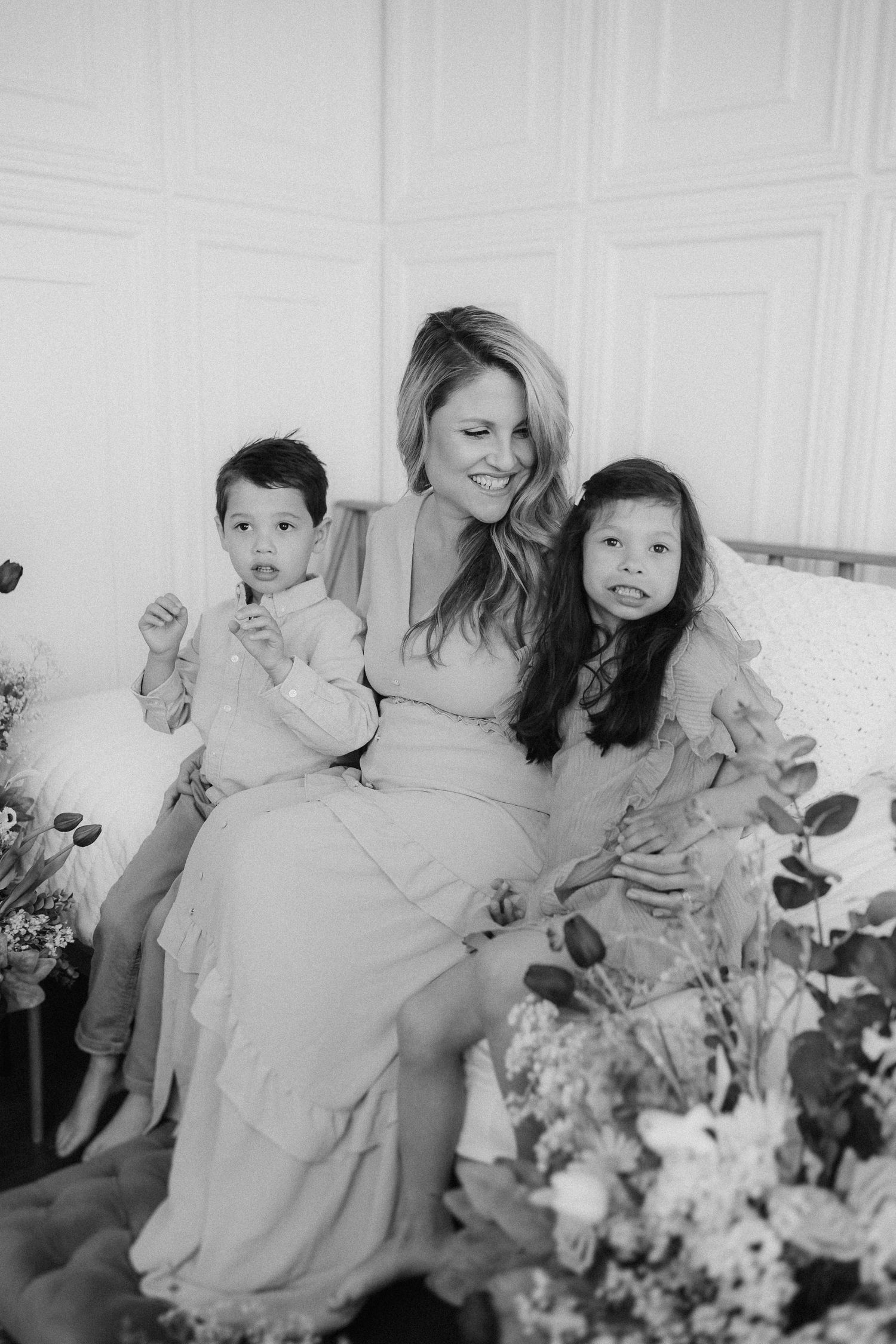 Black and white photo series showing joyful moments between parent and children playing while sitting in a white room.