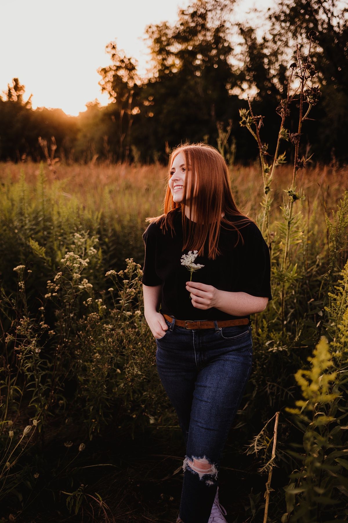 Candid sunset portrait in field holding dried flowers.