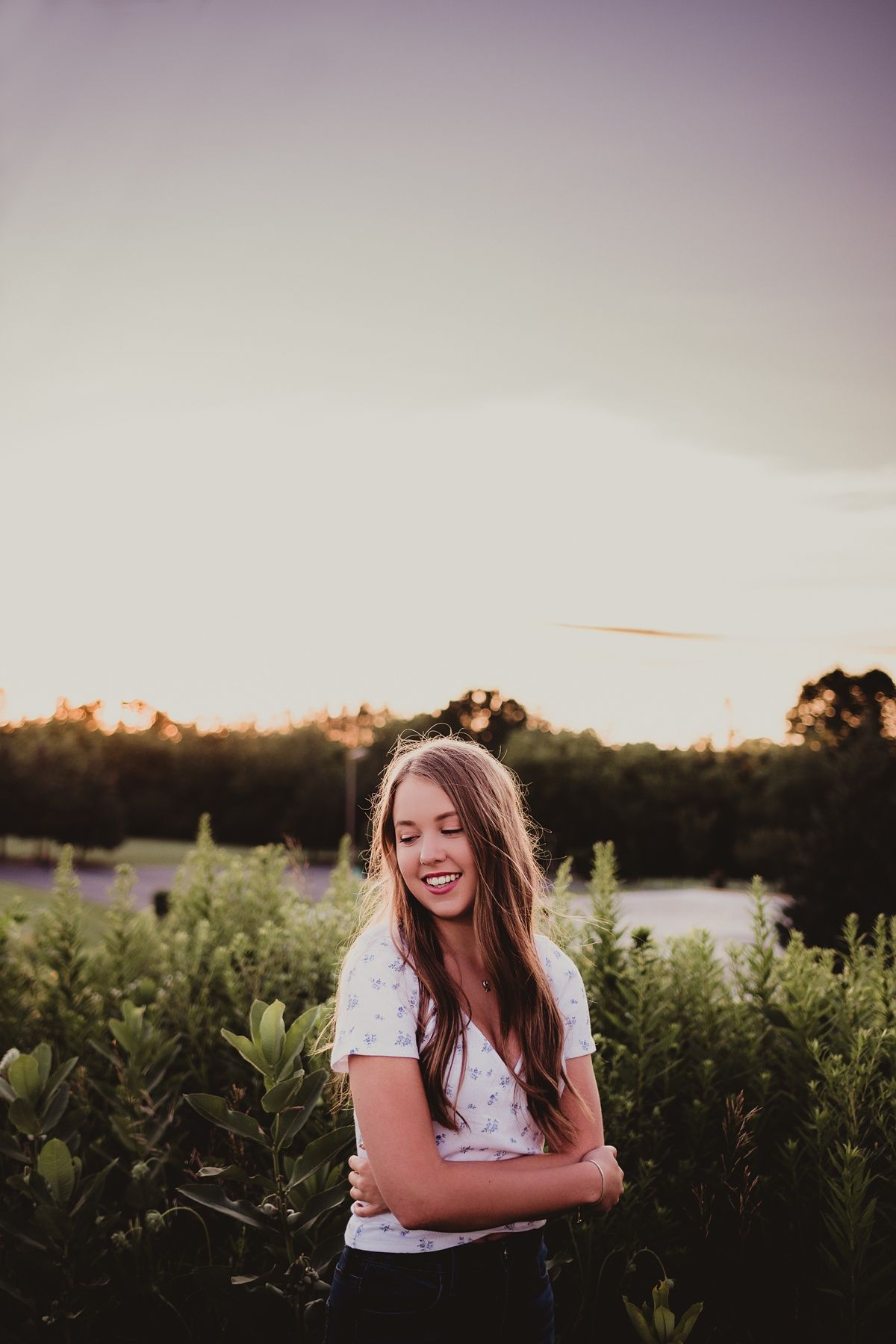 A joyful outdoor portrait against greenery at sunset.