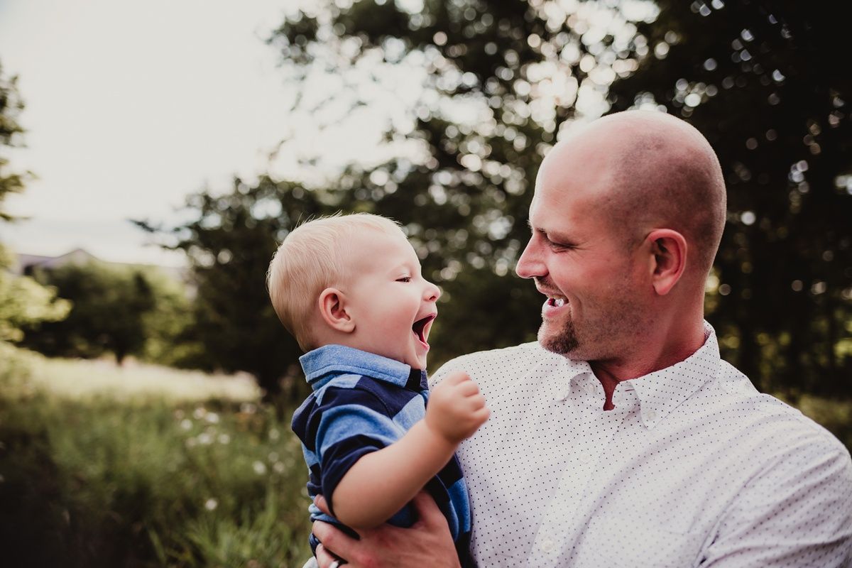 Heartwarming moment between adult and child laughing together outside.
