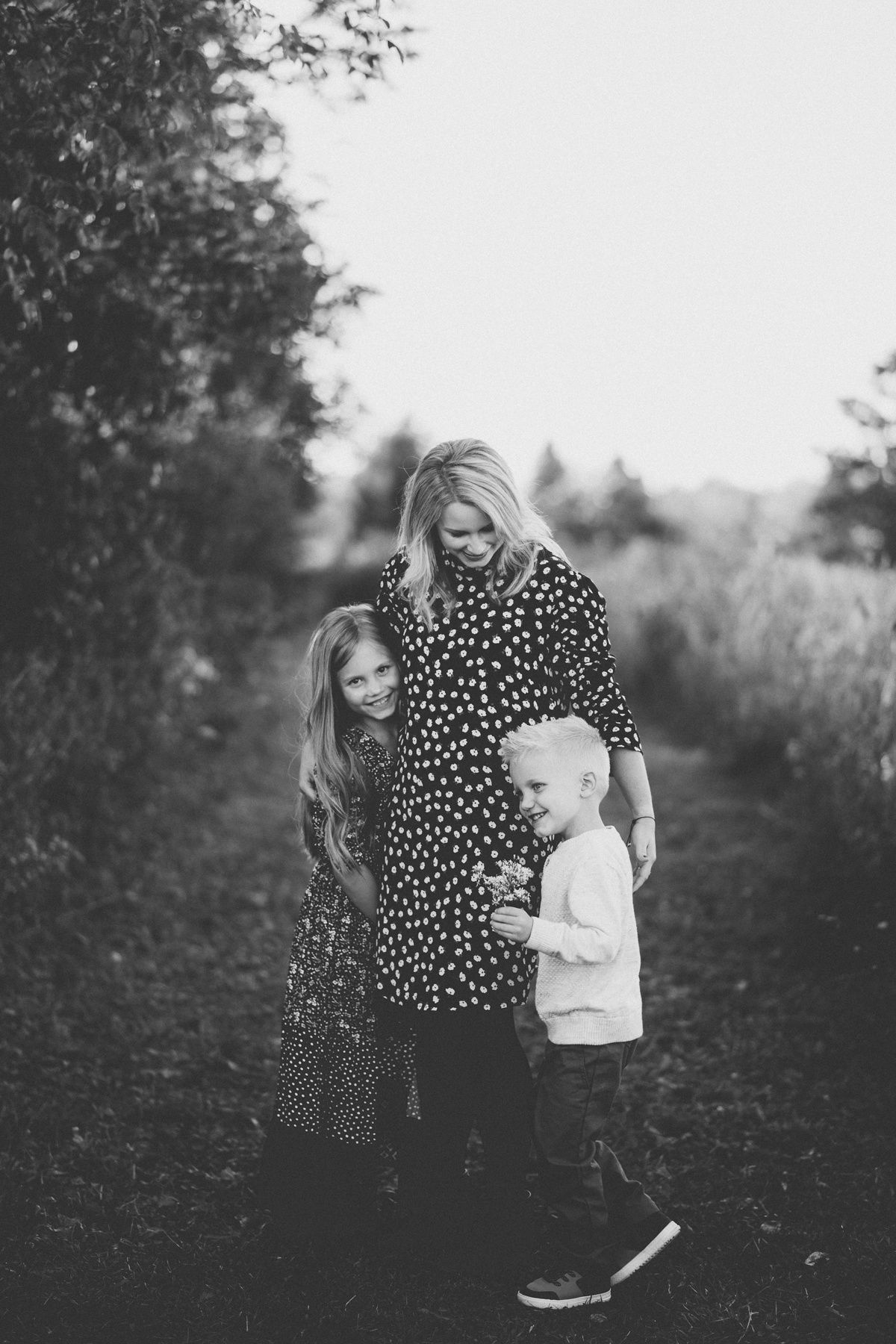 Black and white family portrait on outdoor path through nature.