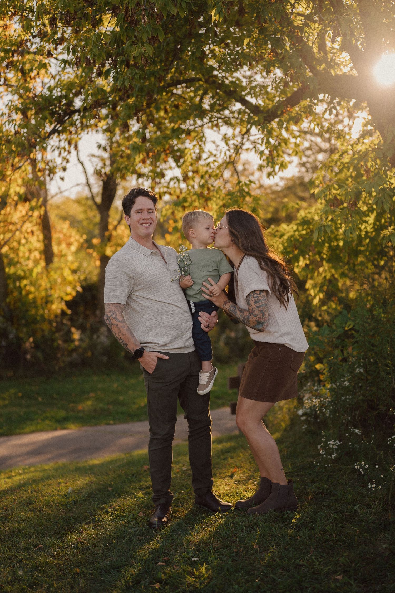 Family enjoying a golden sunset moment together in a park setting with trees.