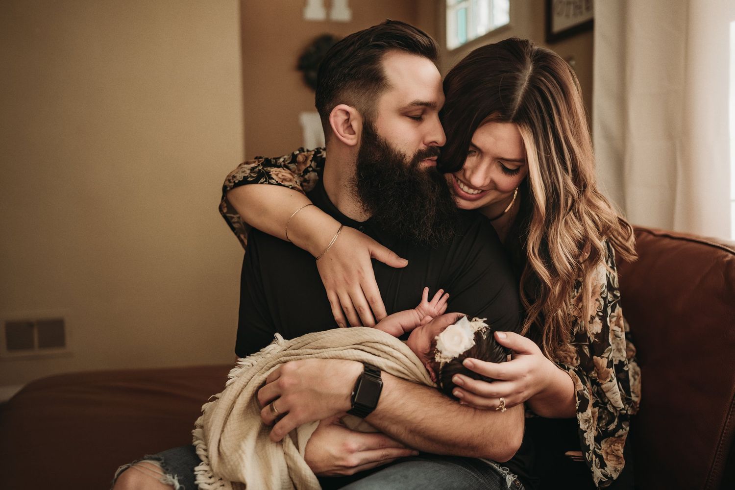 Family sharing tender moment together on brown leather couch.