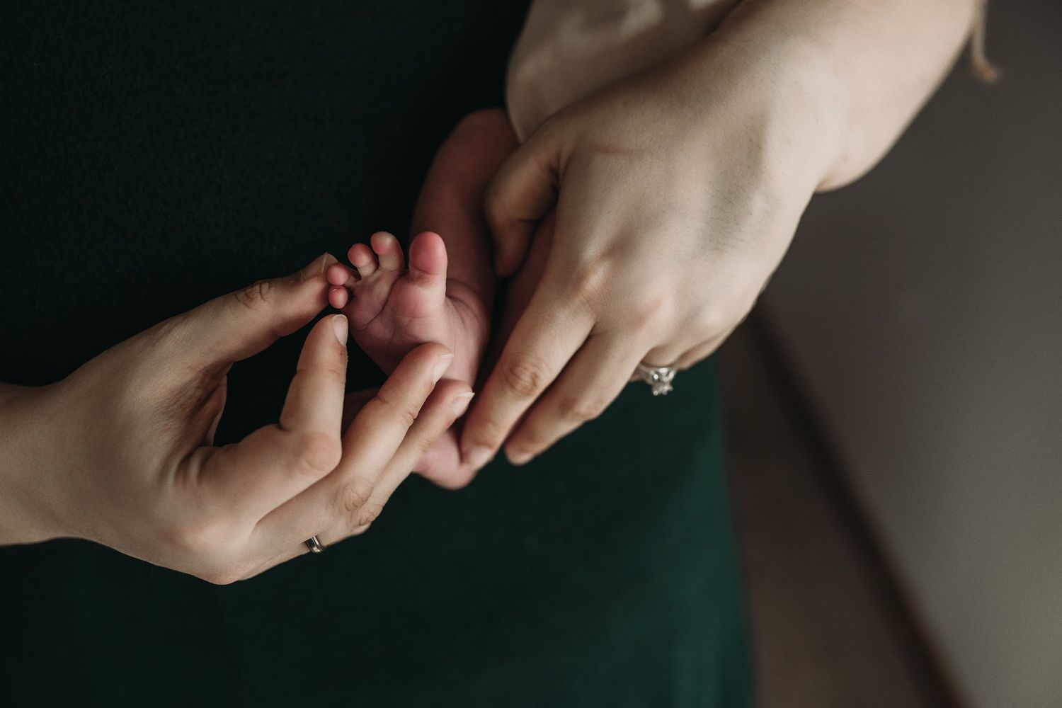 Closeup of tiny newborn baby feet being held by gentle hands.