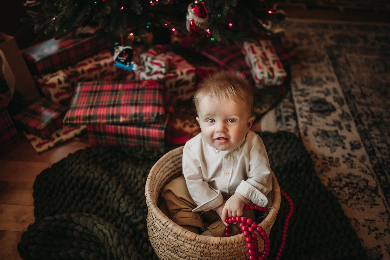 Festive holiday scene featuring a woven basket and red beads near a decorated Christmas tree.
