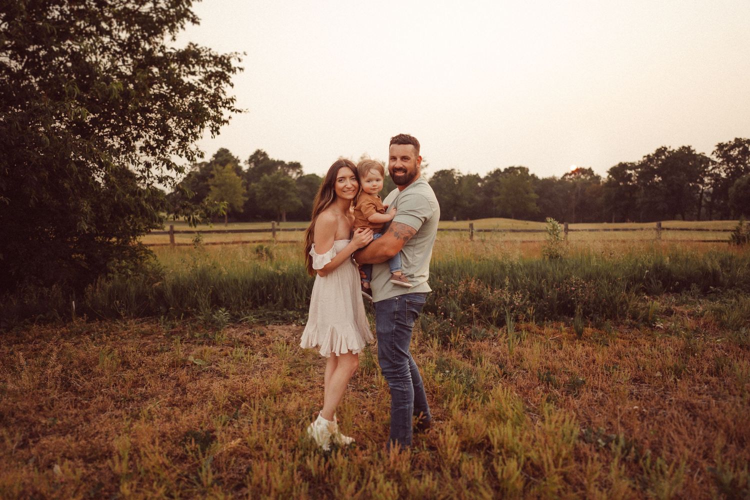 A loving family embrace photographed in a golden field at dusk.
