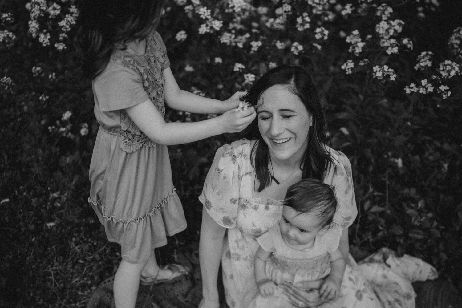 A black and white candid moment of people playing in a flowering garden.