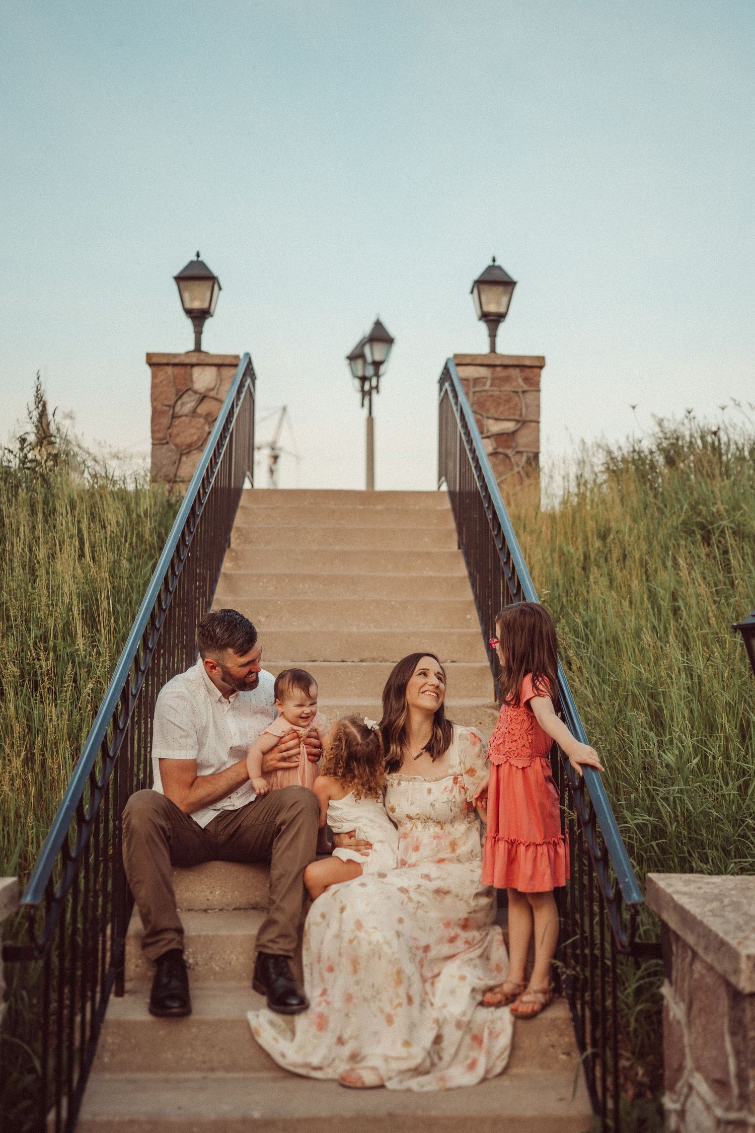 A family gathering on ornate stone steps with decorative lampposts at sunset.
