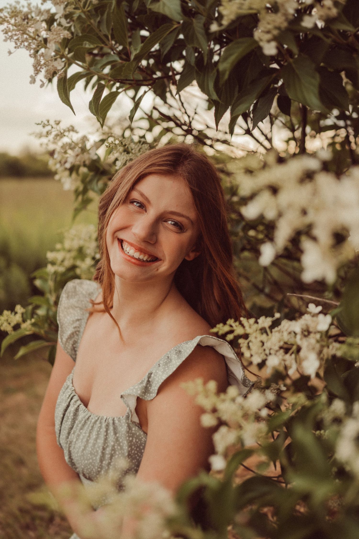 Natural portrait among blooming tree branches in warm evening sunlight.