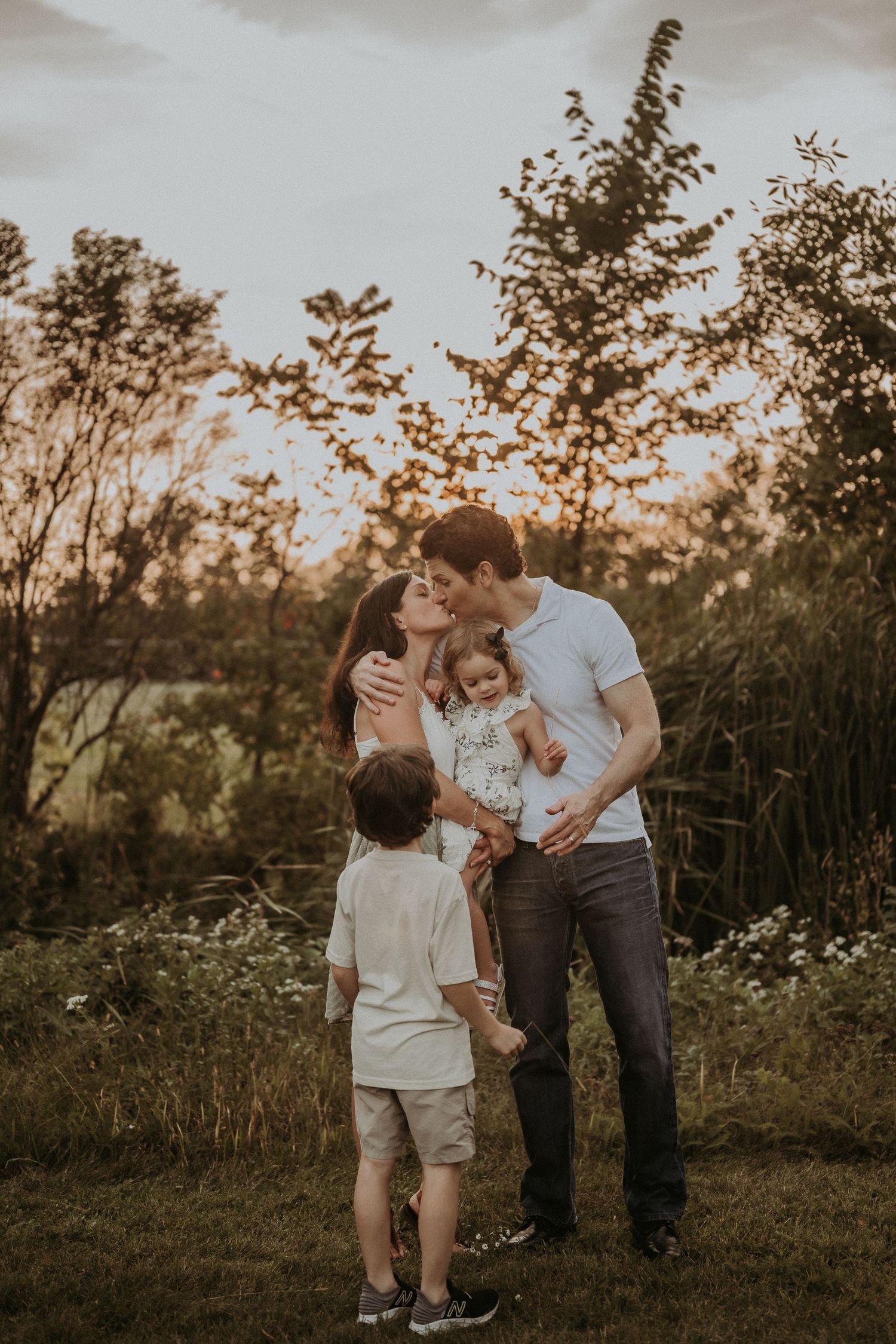 A family shares an intimate moment together in a field during sunset.