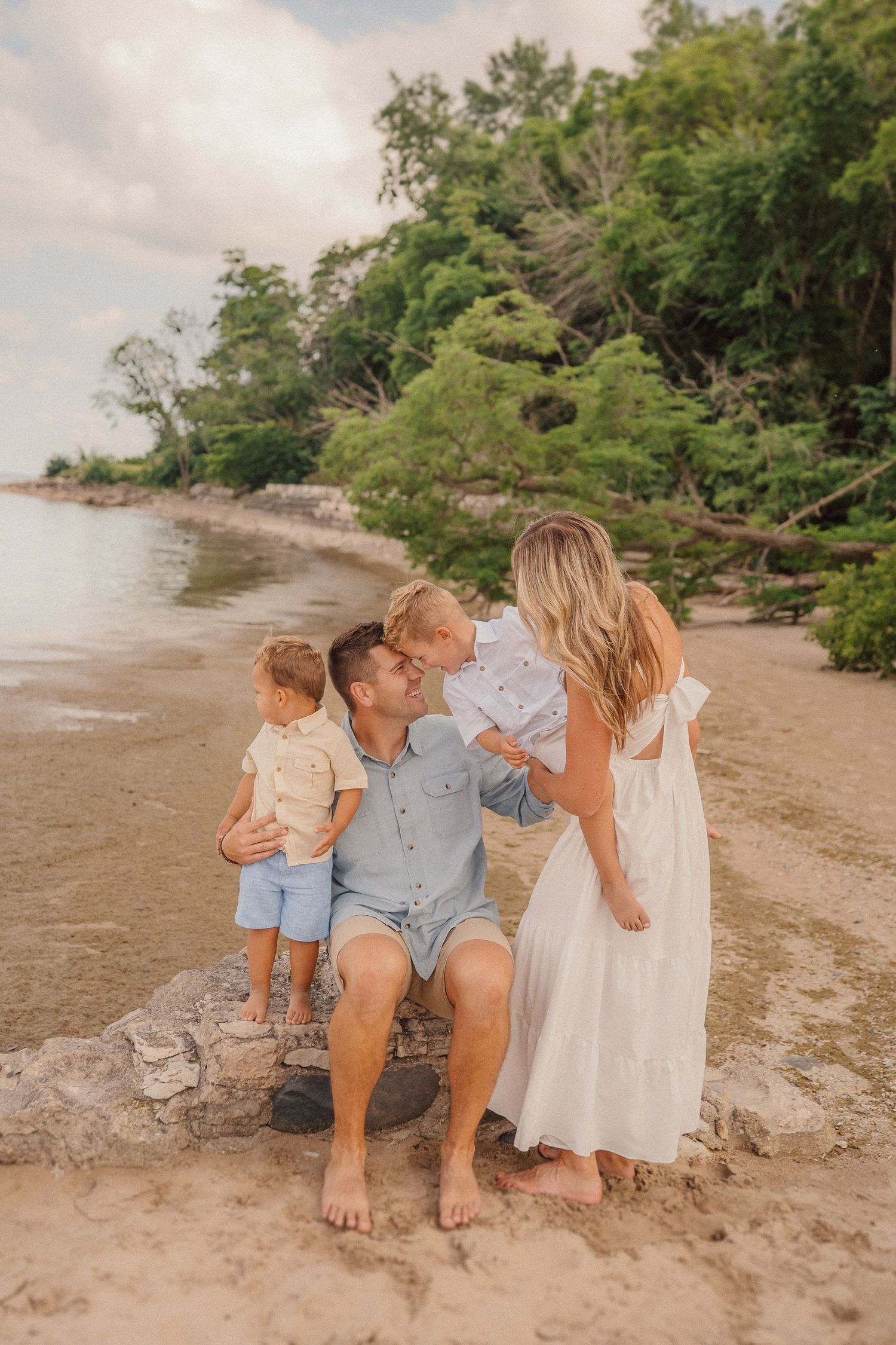 Group sitting together on sandy beach near water's edge during golden hour.